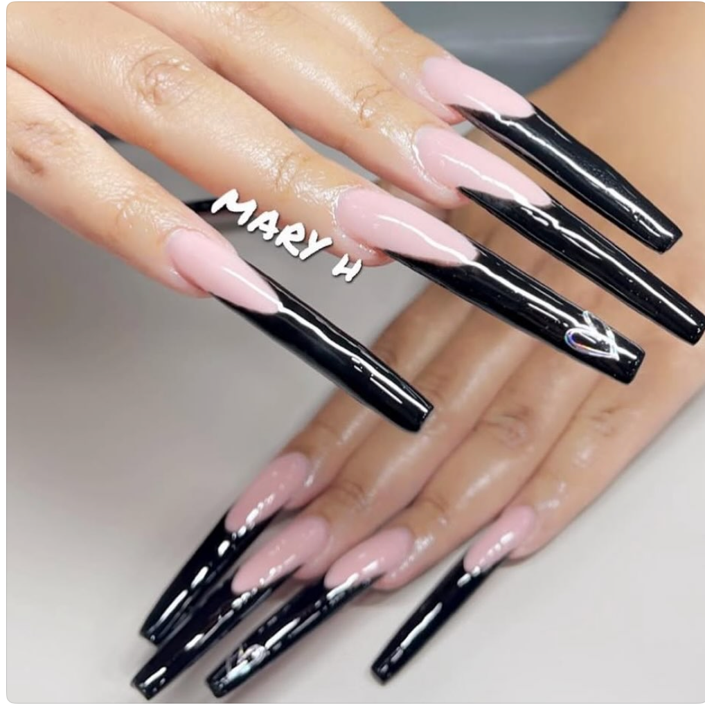 A close-up of hands with long, coffin-shaped nails painted in pink and black, with the black nails featuring small heart designs.