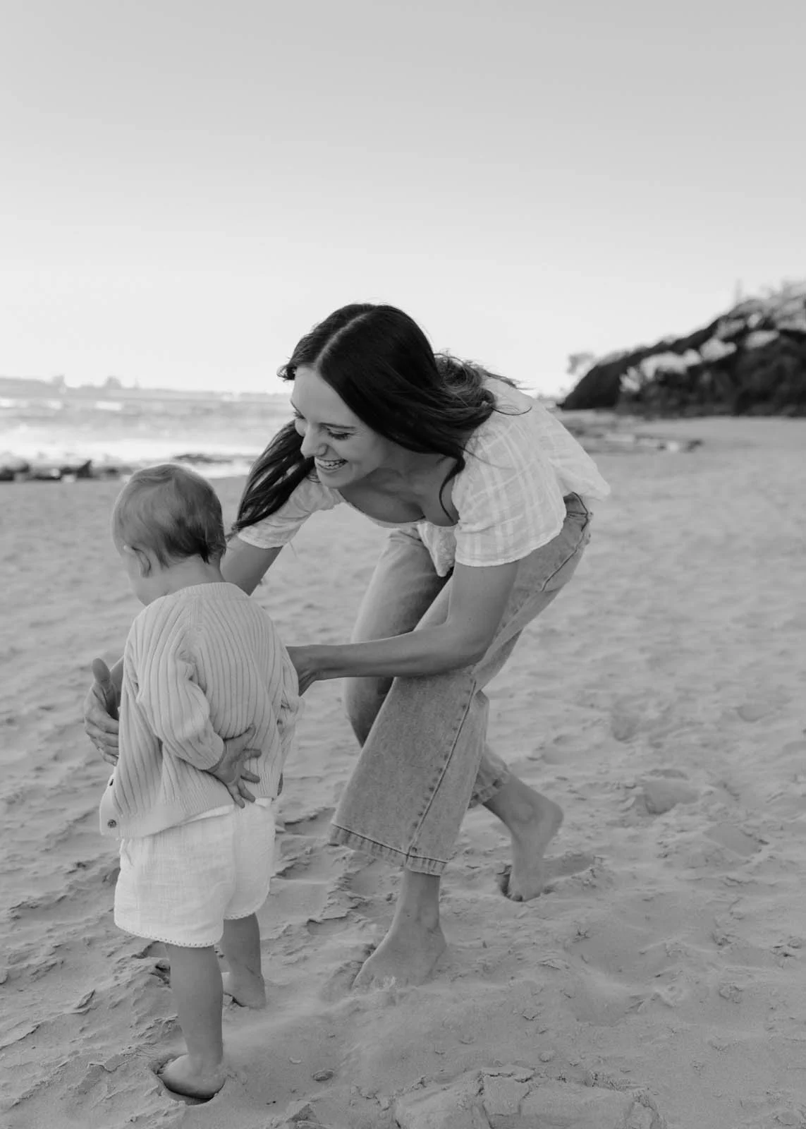 gold-coast-family-photographer-mother-guiding-baby-on-beach.jpg