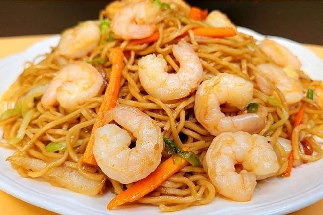Plate of stir-fried noodles with shrimp, carrots, and green onions