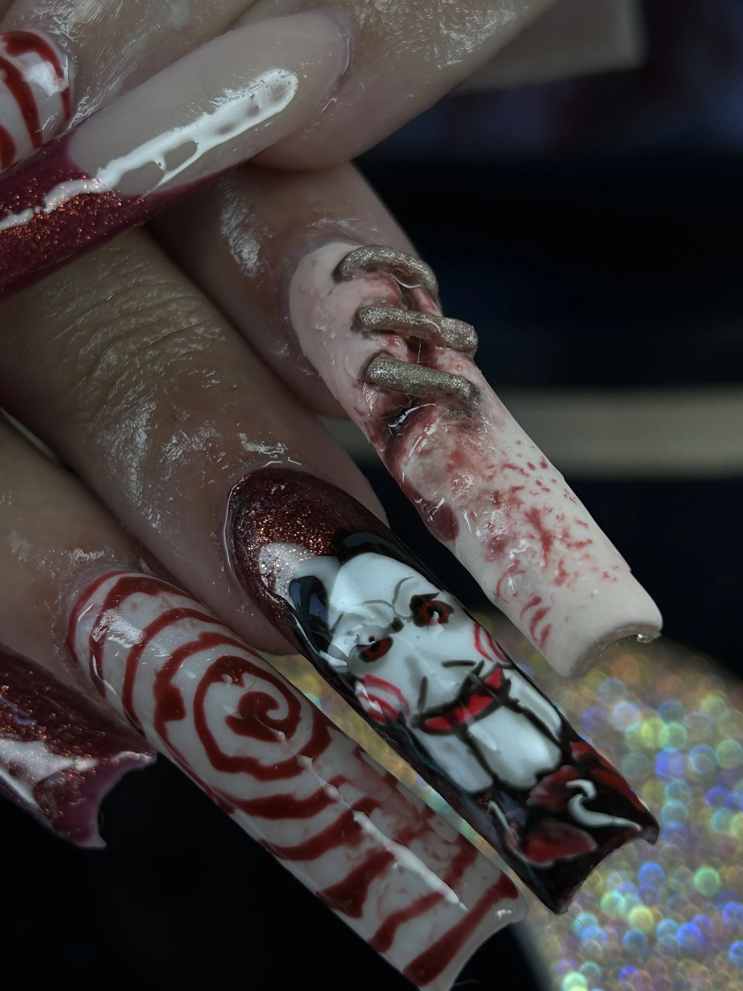 Close-up of decorative nail art with red, white, black, and glittery silver colors on fingernails.