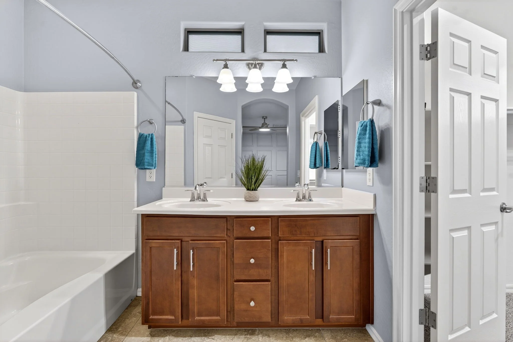 Bathroom with double sink vanity, mirror, and blue towels on towel rings.