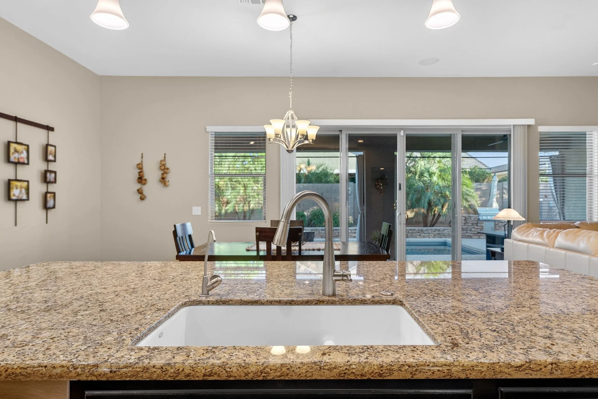 View of a modern kitchen with granite countertop, what appears to be a built-in sink, and a view into a dining area with sliding glass doors leading outside.