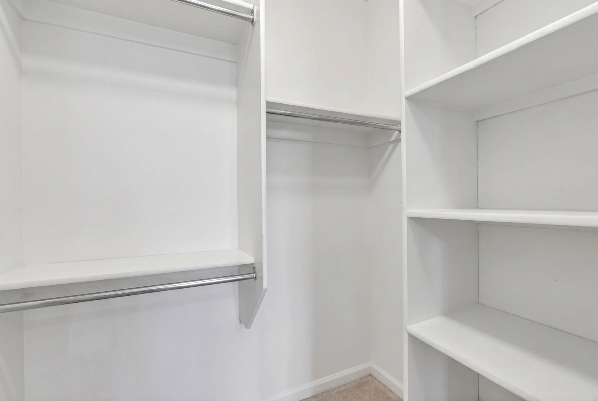 Empty white closet with multiple shelves and hanging rods.