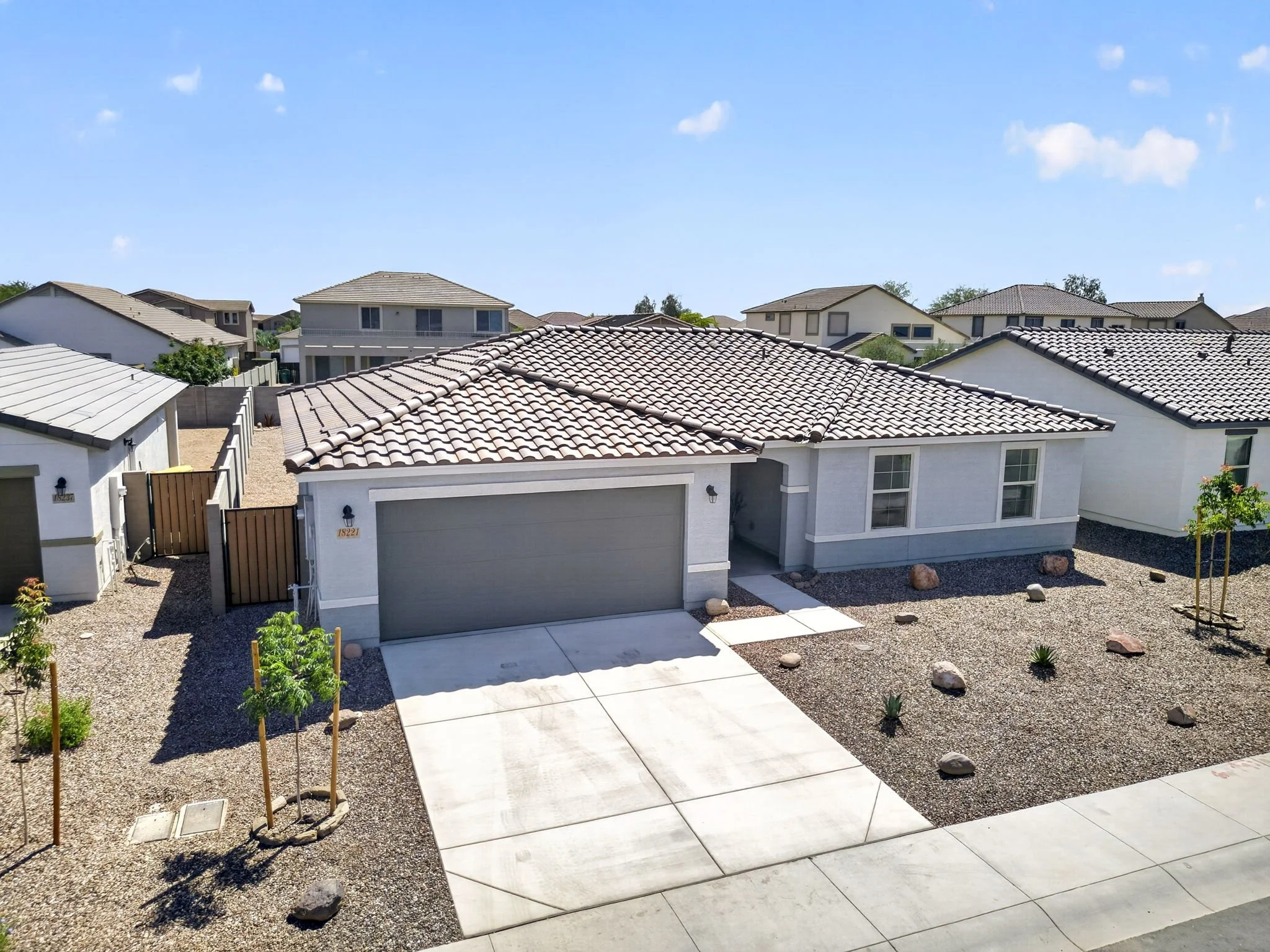 View of multiple suburban houses with tiled roofs in a neighborhood on a sunny day.