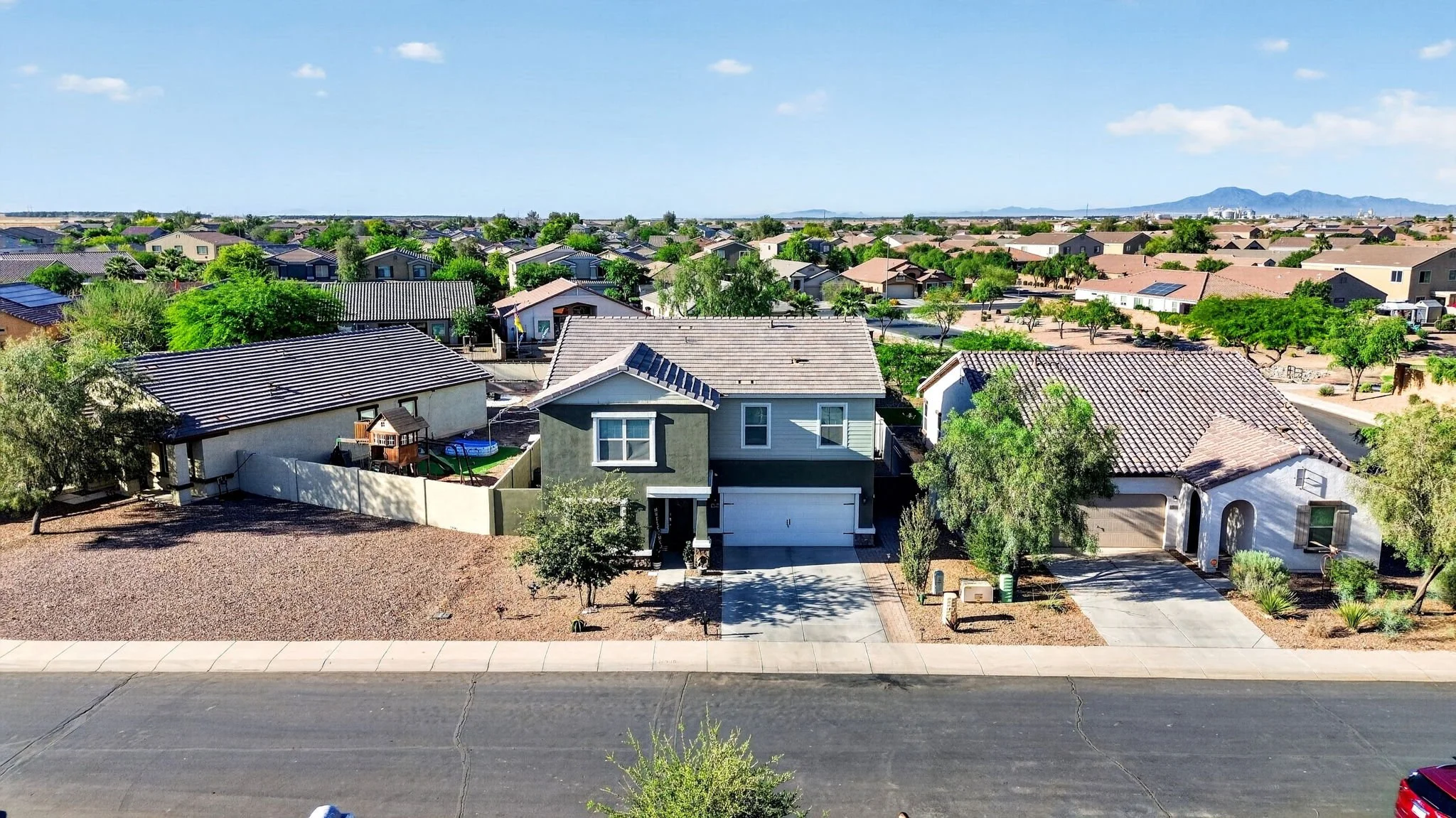 A suburban neighborhood with neatly arranged houses, trees, and a clear blue sky in the background.