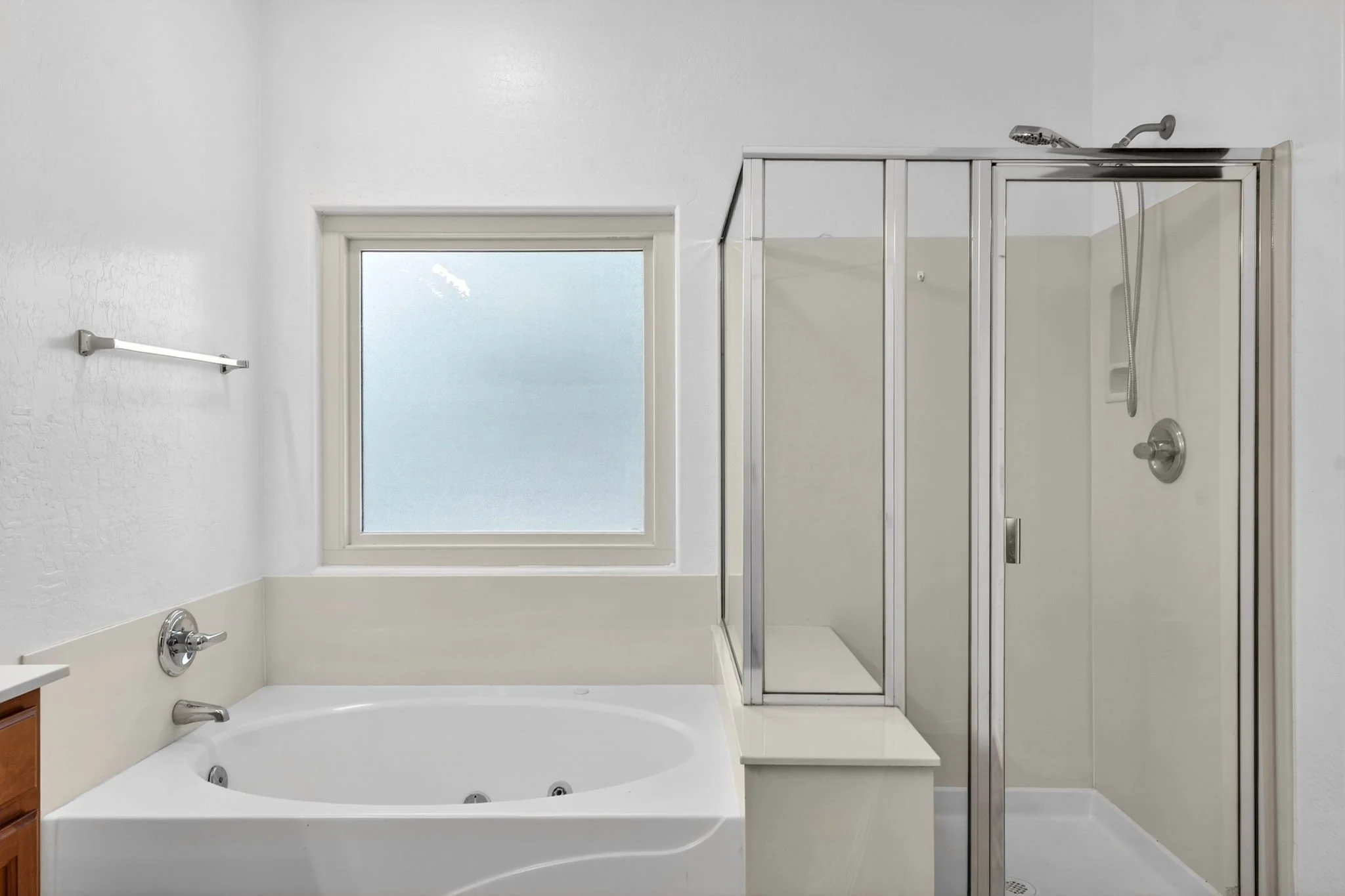 Bathroom with a bathtub, a glass shower enclosure, a window, and white walls.