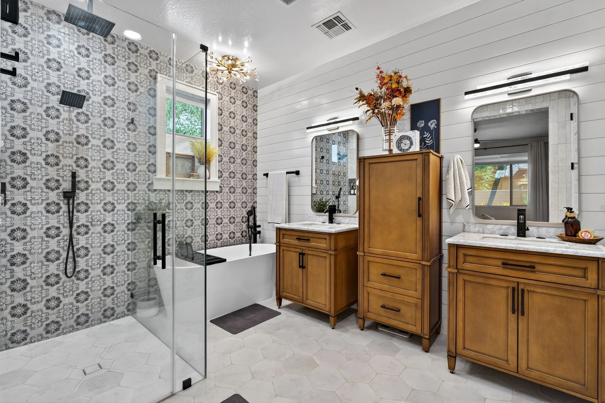 Modern bathroom with a walk-in shower, bathtub, wooden cabinets, white shiplap walls, and a large mirror.