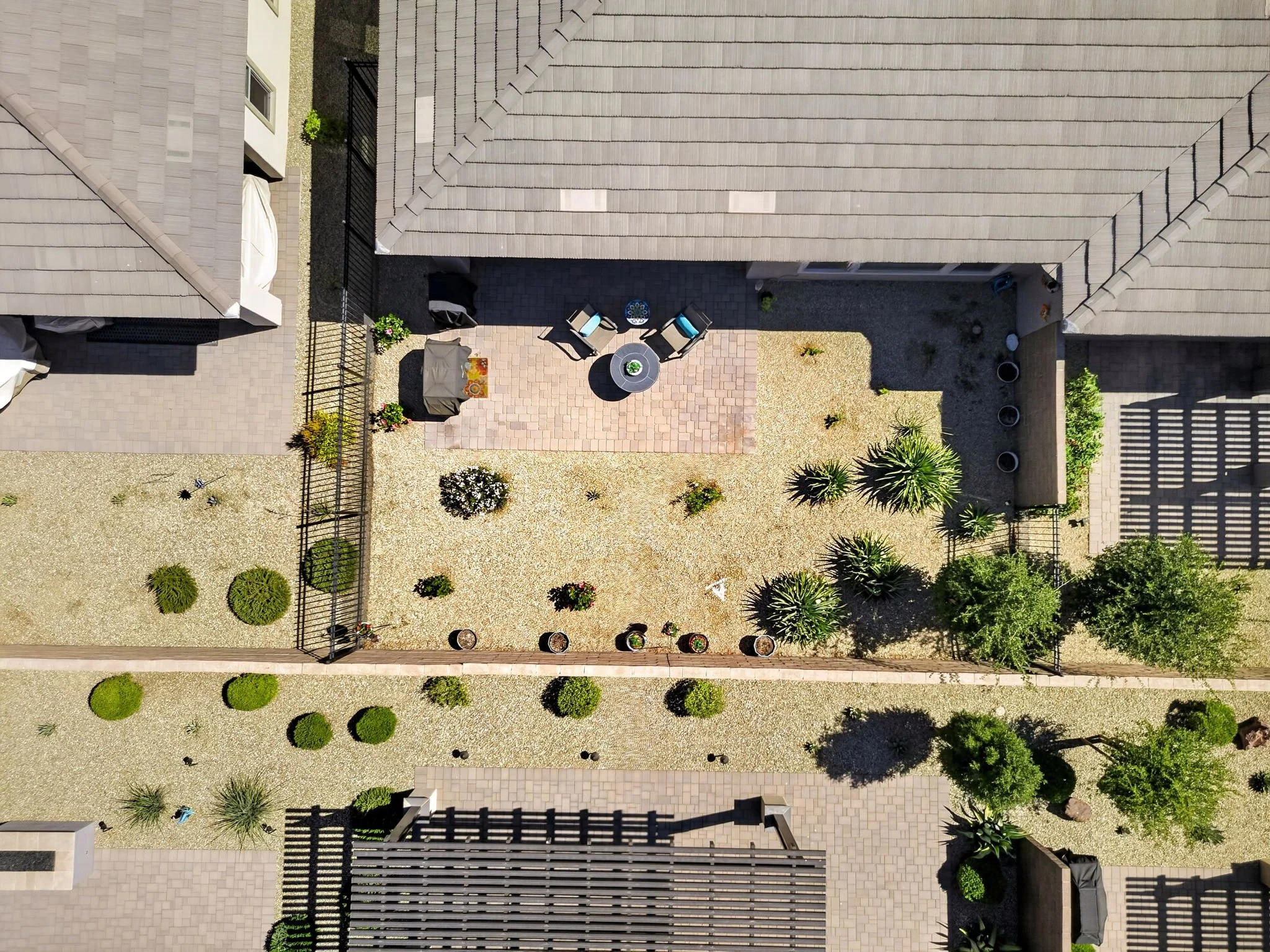 Aerial view of a backyard patio with outdoor furniture, potted plants, and surrounding landscaping.