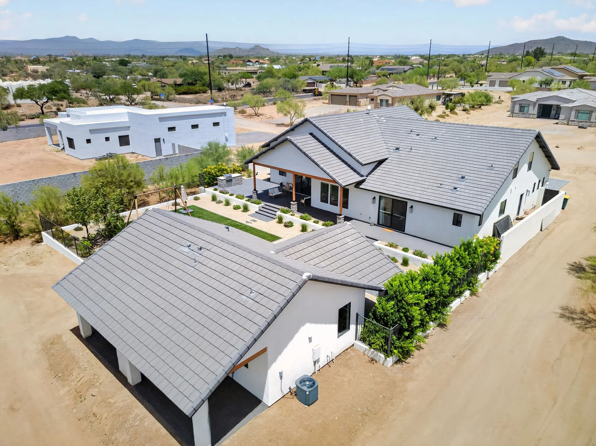  aerial view of a residential neighborhood with modern houses and desert landscaping in a desert city, mountains in the distance.