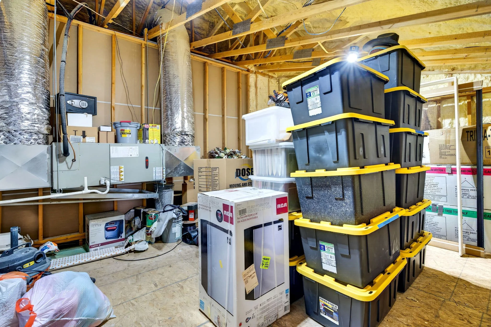 A cluttered garage filled with storage containers, boxes, and household items.