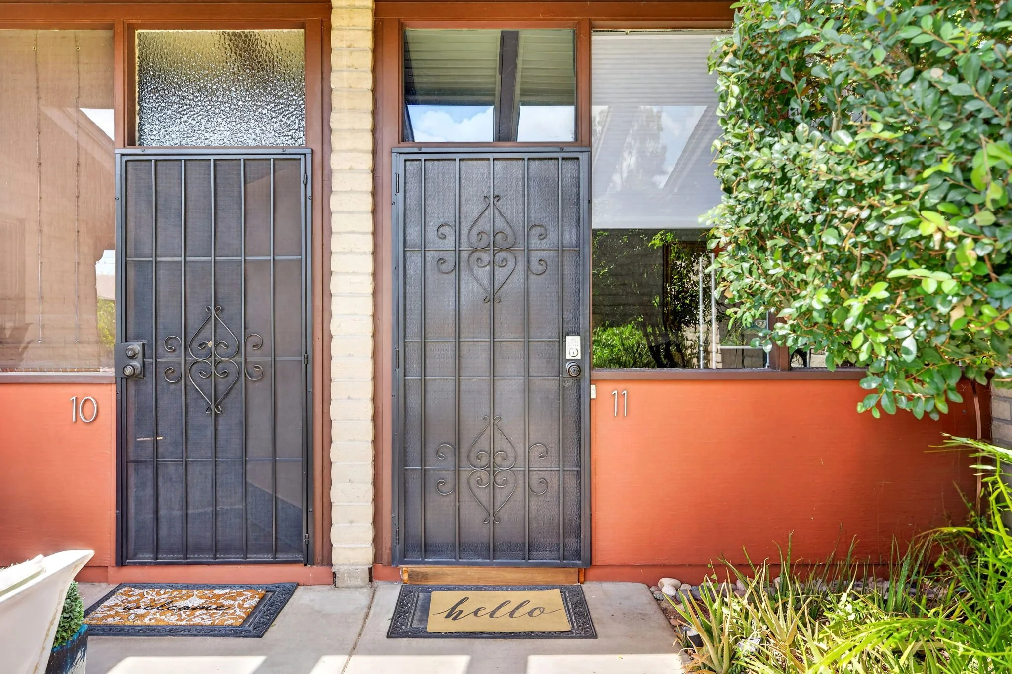 Front entrance of a house with two black wrought iron gates, house number 10 and 11, and a 