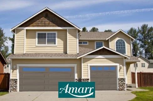 Two-story house with a beige exterior, stone accents, and two garage doors, situated in a suburban neighborhood.
