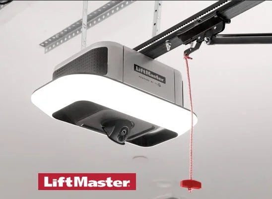 Garage door opener with a safety infrared sensor and red cord, branded LiftMaster, mounted on ceiling.