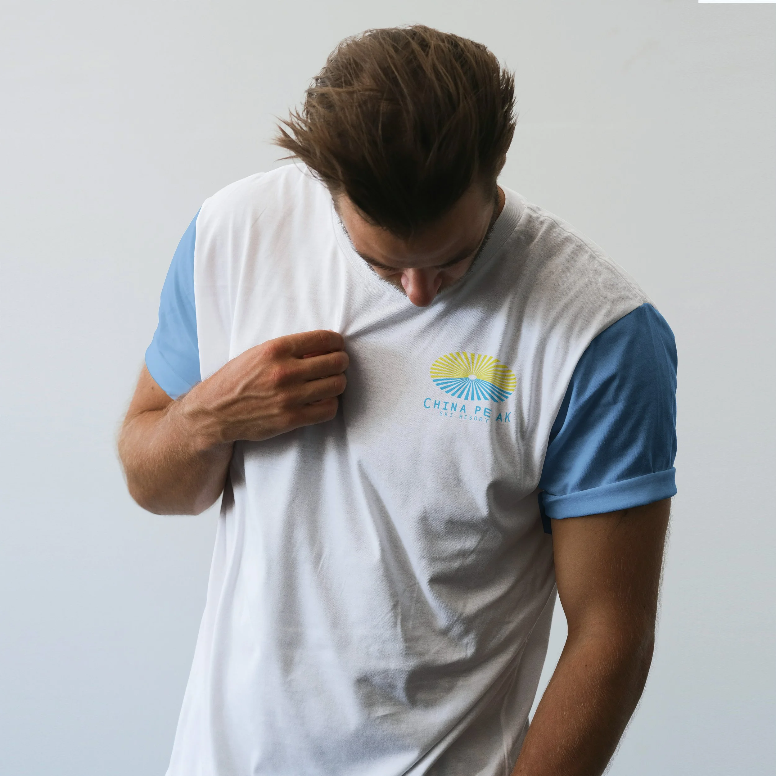 Photo of guy looking down at full color China Peak Ski Resort logo on left chest of t-shirt