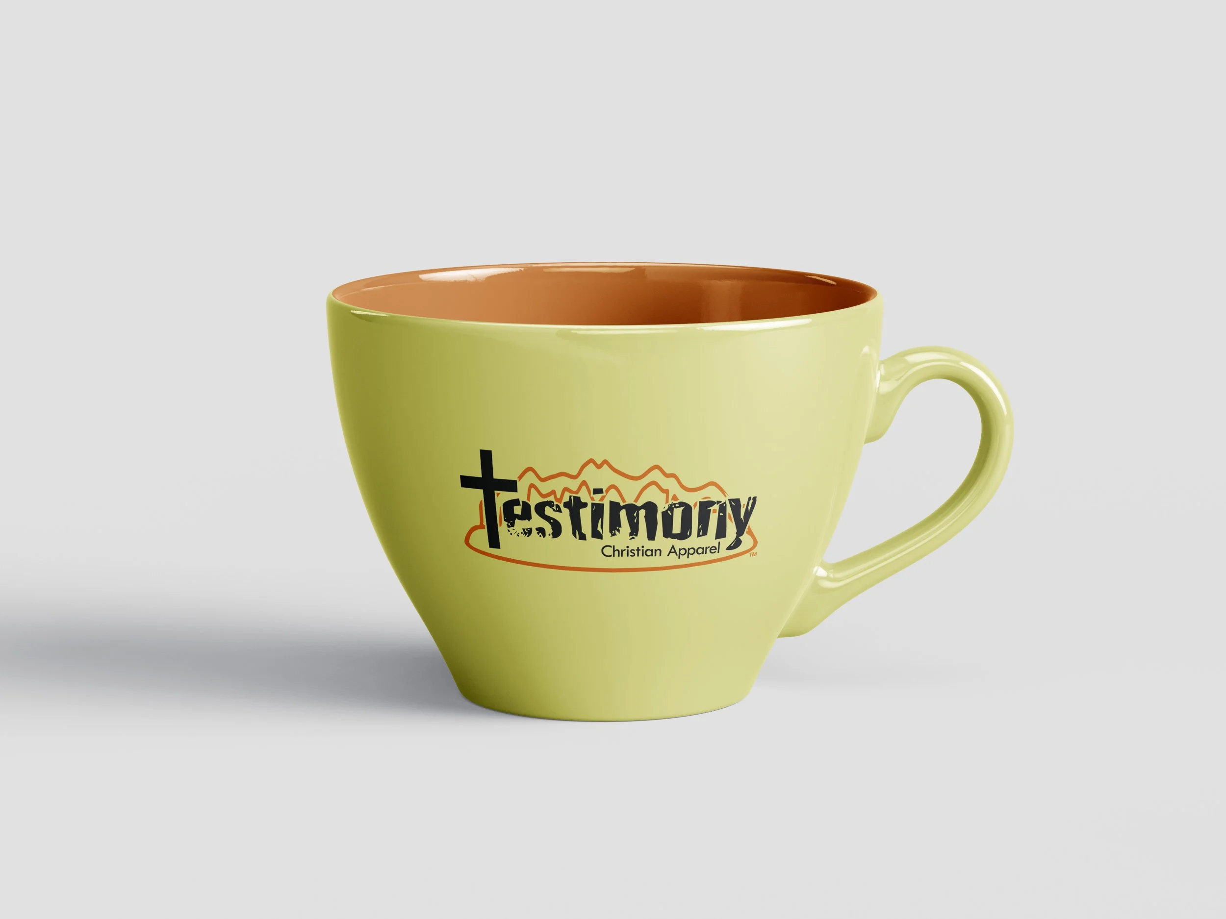 Photo of yellow ceramic coffee cup with full color Testimony Christian Apparel logo