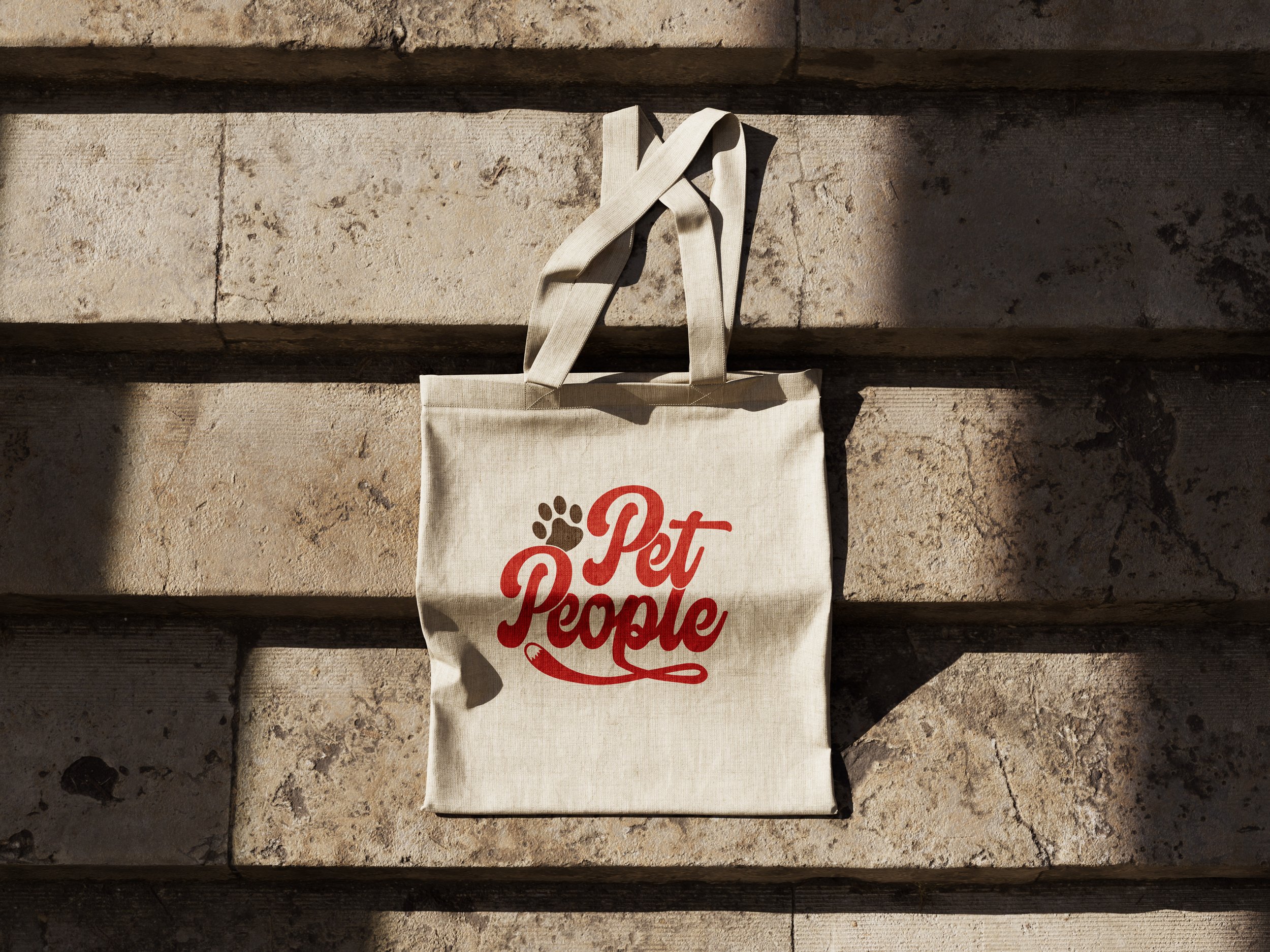 Photo of cotton canvas tote bag laid out over steps with light and shadows, showing full color Pet People logo