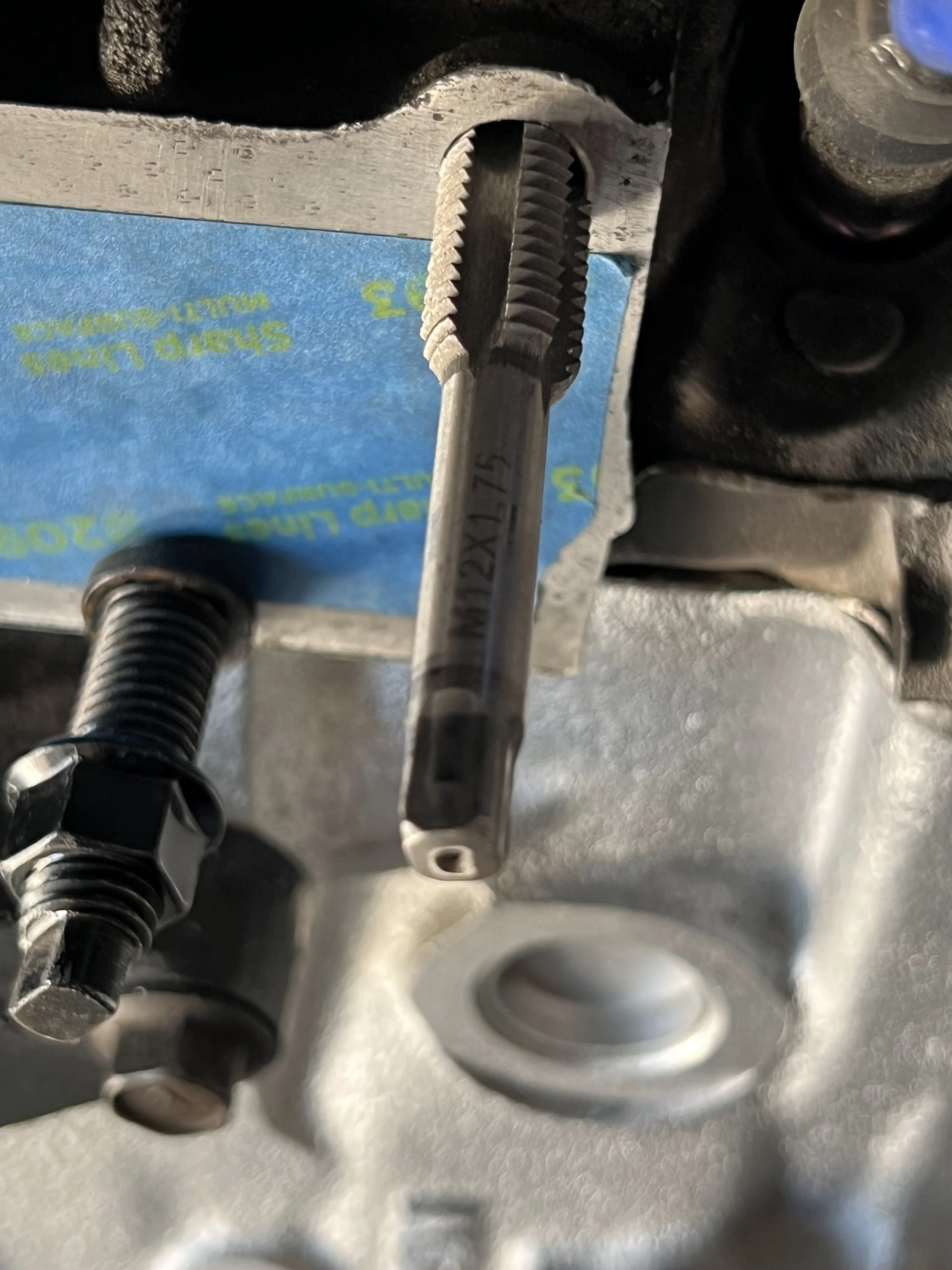 Close-up of a thread tap ready to fix the stripped exhaust stud hold on a Nissan CA20E cylinder head.