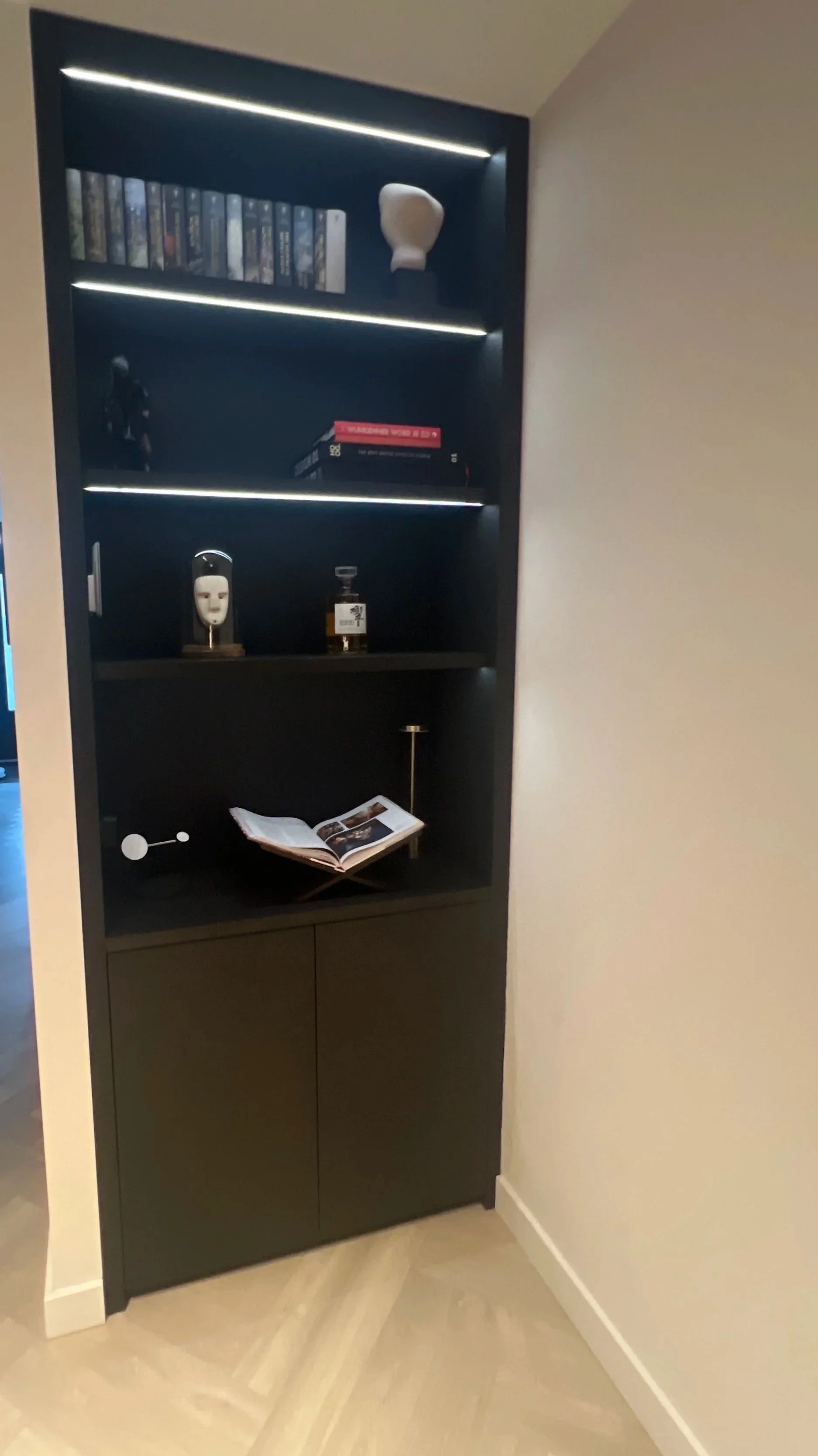 Donkere boekenplank met boeken, decoratieve voorwerpen en een open tijdschrift, in een woninginterieur.