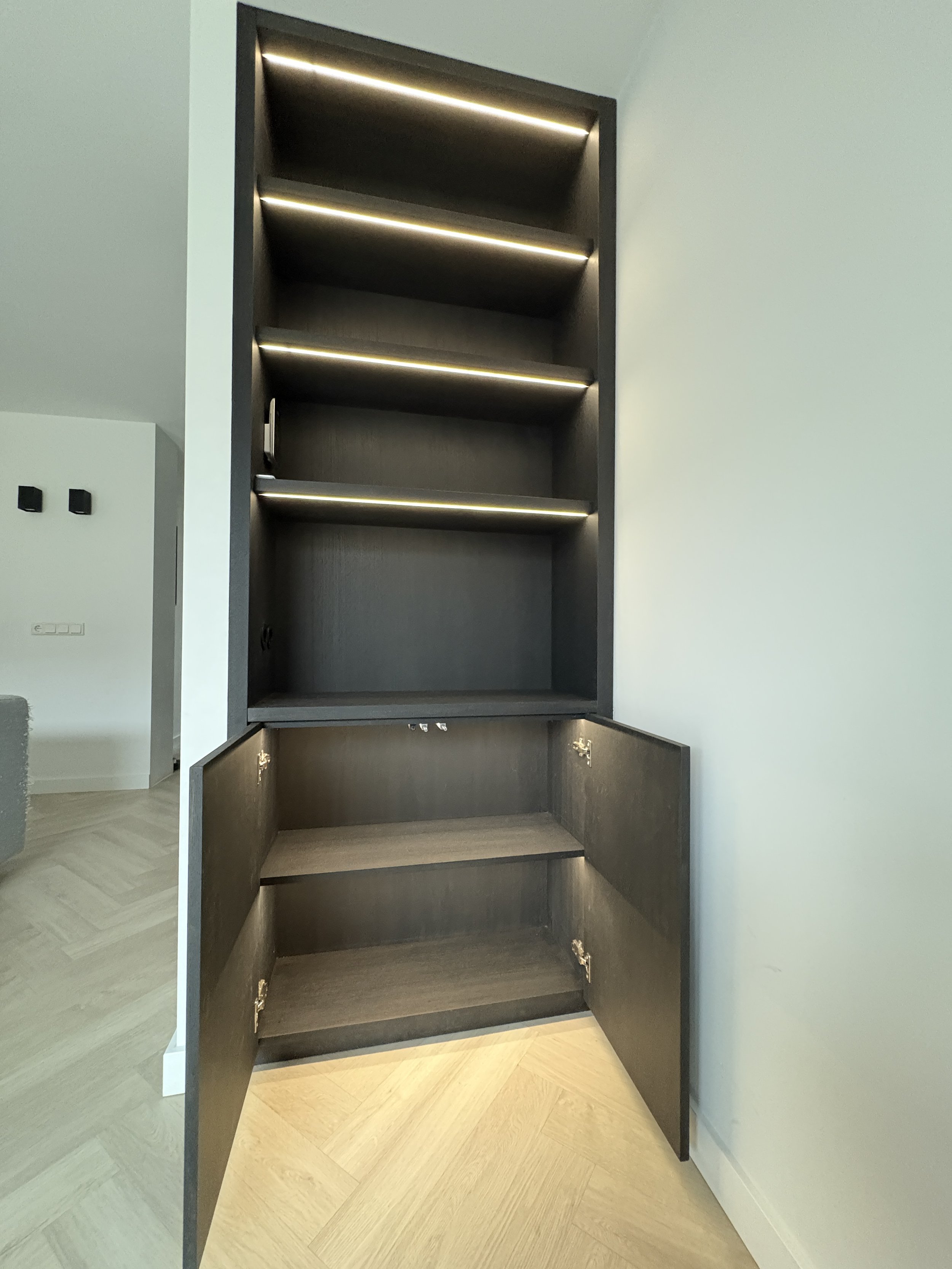 Een zwarte houten kast met vier open bovenrekken en twee gesloten onderkasten, allemaal met ingebouwde verlichting.