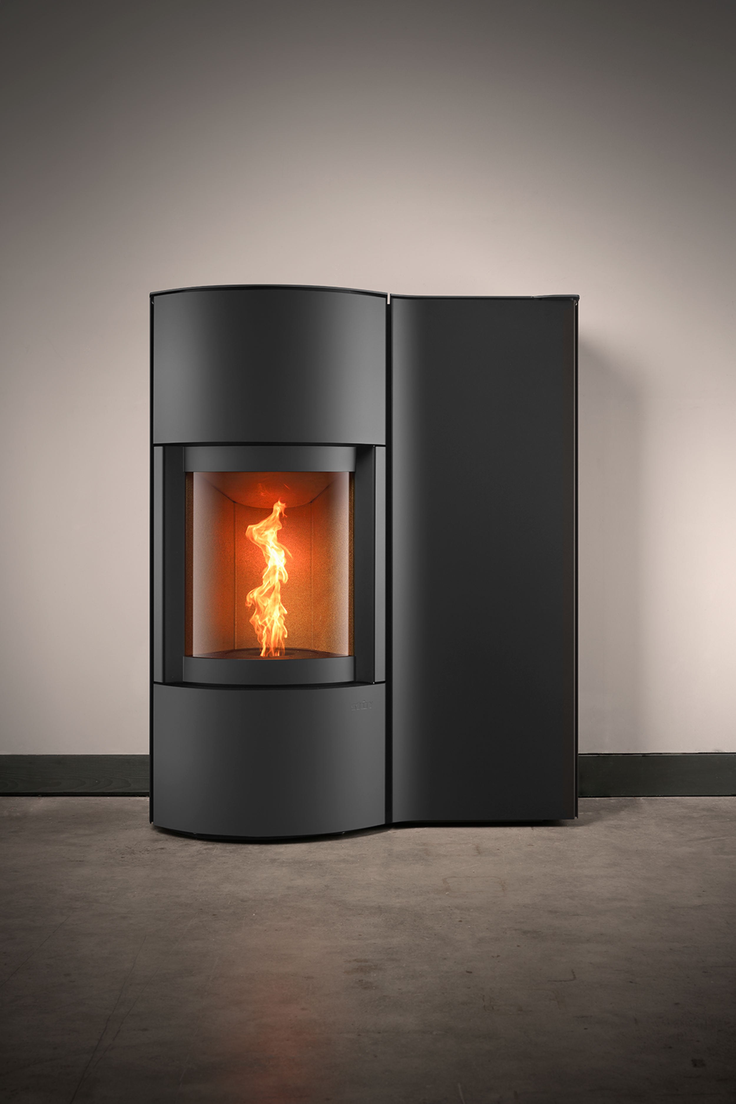 Moderne zwart kachel met brandend vuur, geplaatst tegen een beige muur op een betonnen vloer.
