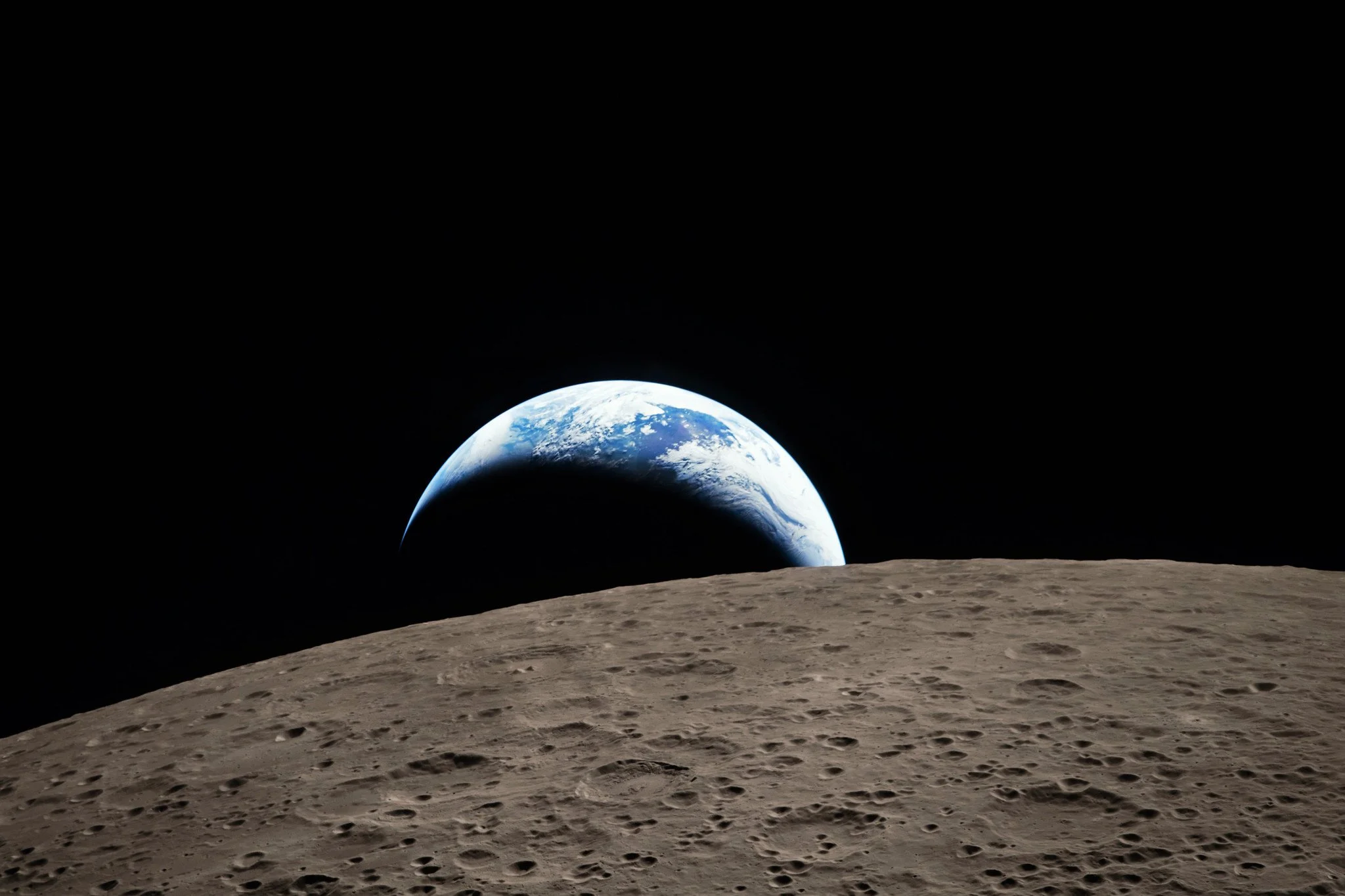 Earth as a thin crescent rising over the curved grey limb of the Moon, photographed from the Artemis II spacecraft.
