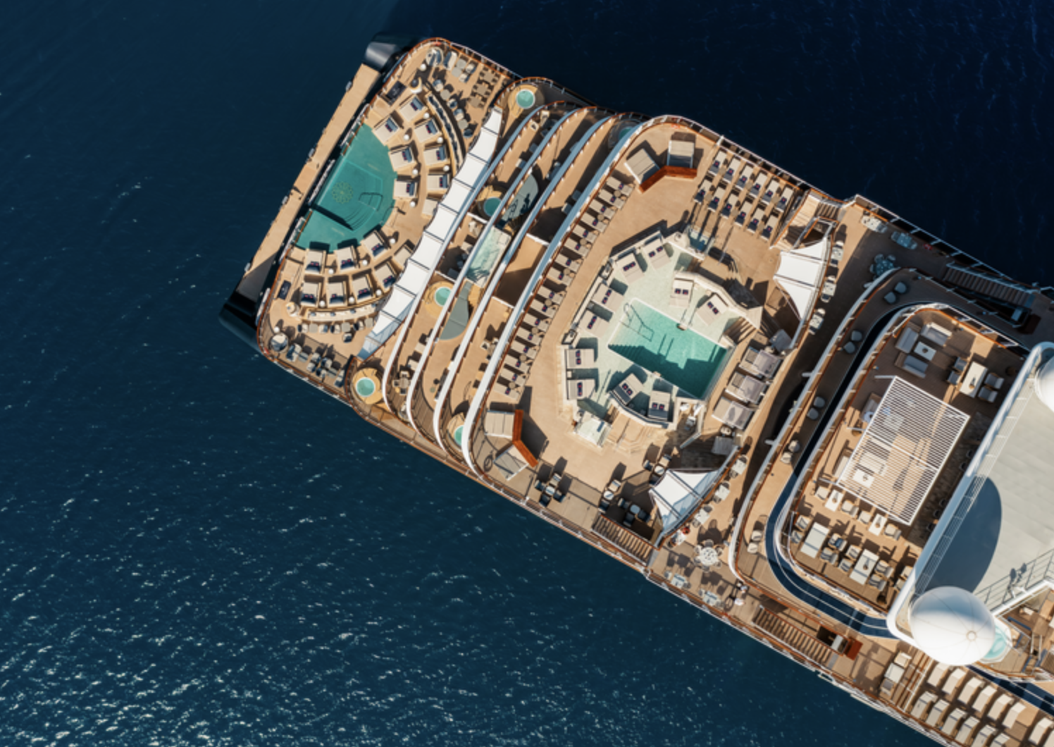 Aerial view of a cruise ship deck featuring pools, lounge chairs, and seating areas, surrounded by open ocean.