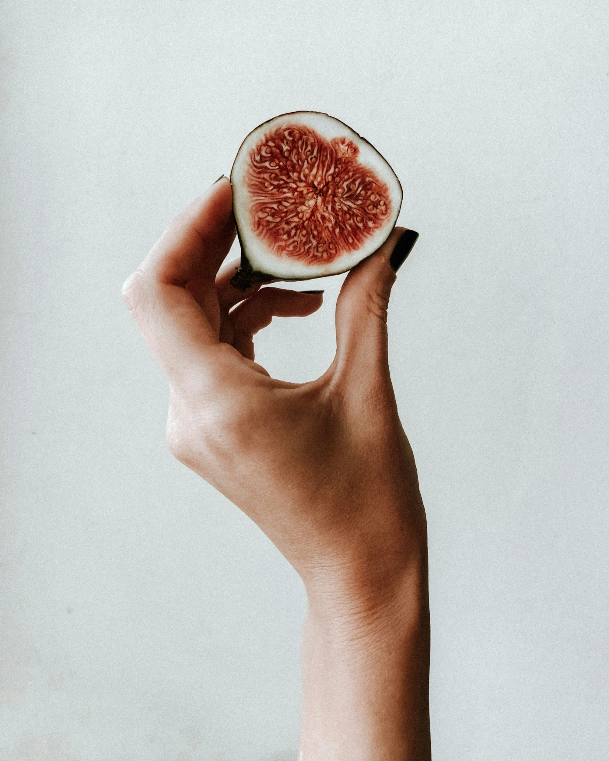 Halve verse vijg in de hand. Voedzame en natuurlijke voeding voor gezondheid en vitaliteit.