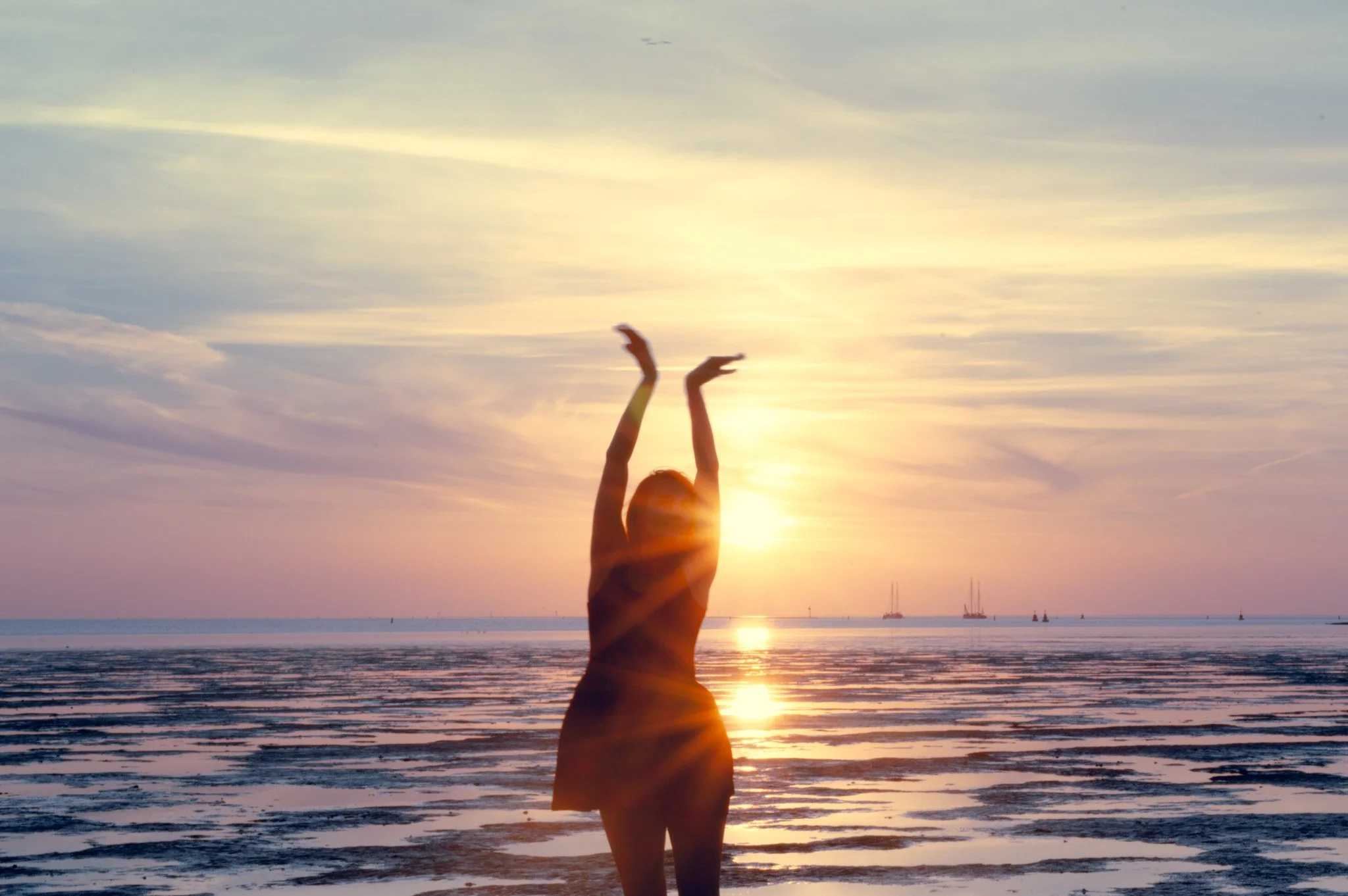Vrouw op het strand tijdens zonsondergang. Rust, balans, persoonlijke groei en bewust leven.