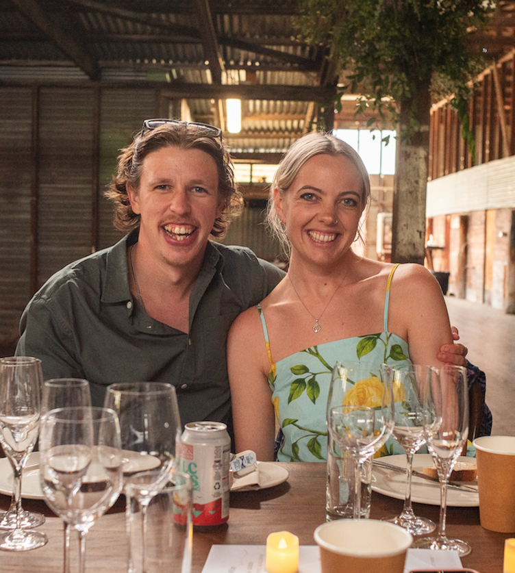 A man and woman sitting together at a wedding guest table in a barn.