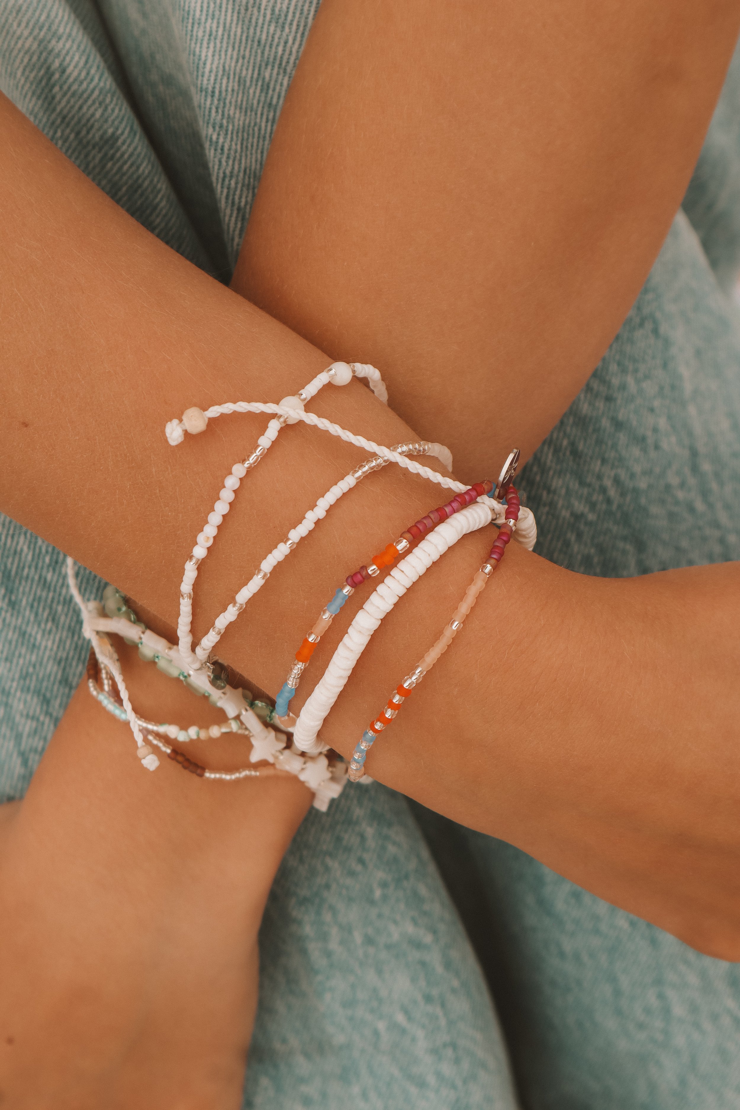 Close-up of a person's arm showing multiple colorful beaded bracelets.