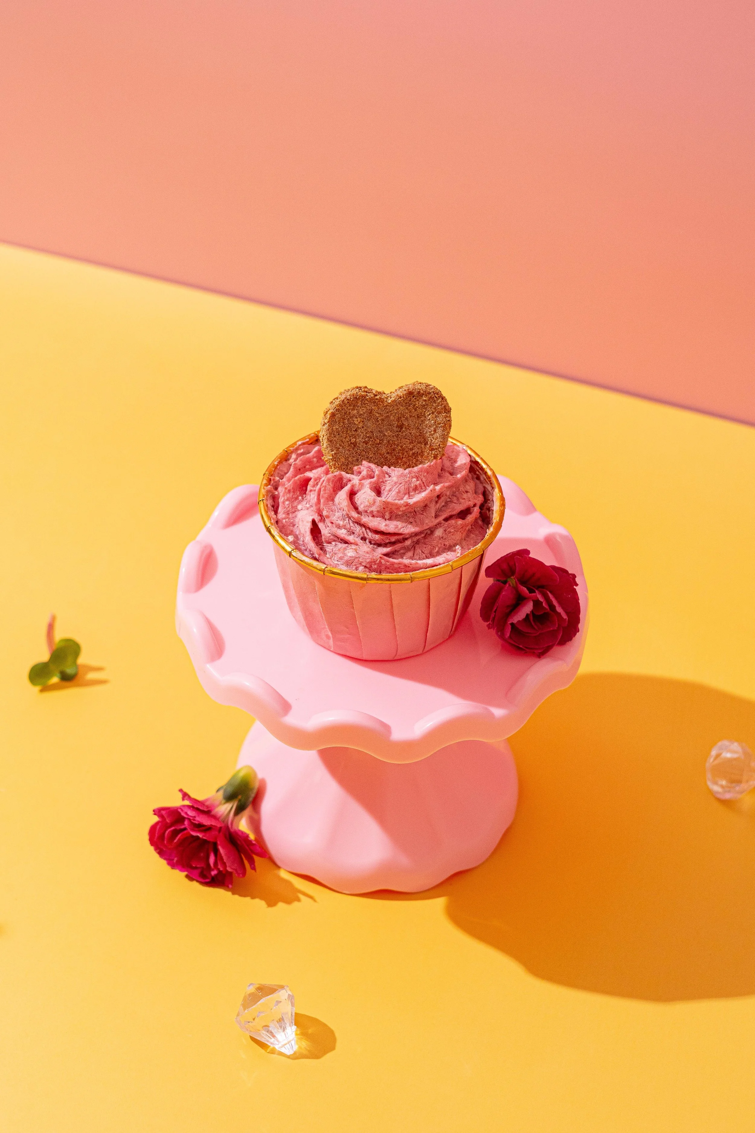 Cupcake gourmet para perros con crema rosa sobre stand de diseño, repostería canina artesanal en el barrio de Ibiza, Madrid, ideal para merendar tras un paseo por el Retiro