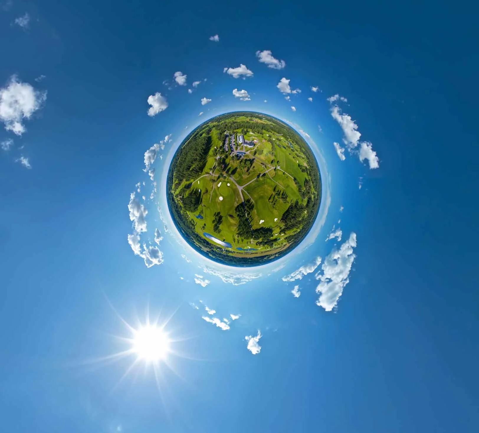 Stereographic projection of a landscape with blue sky and clouds, grassy golf course, and bright sun.