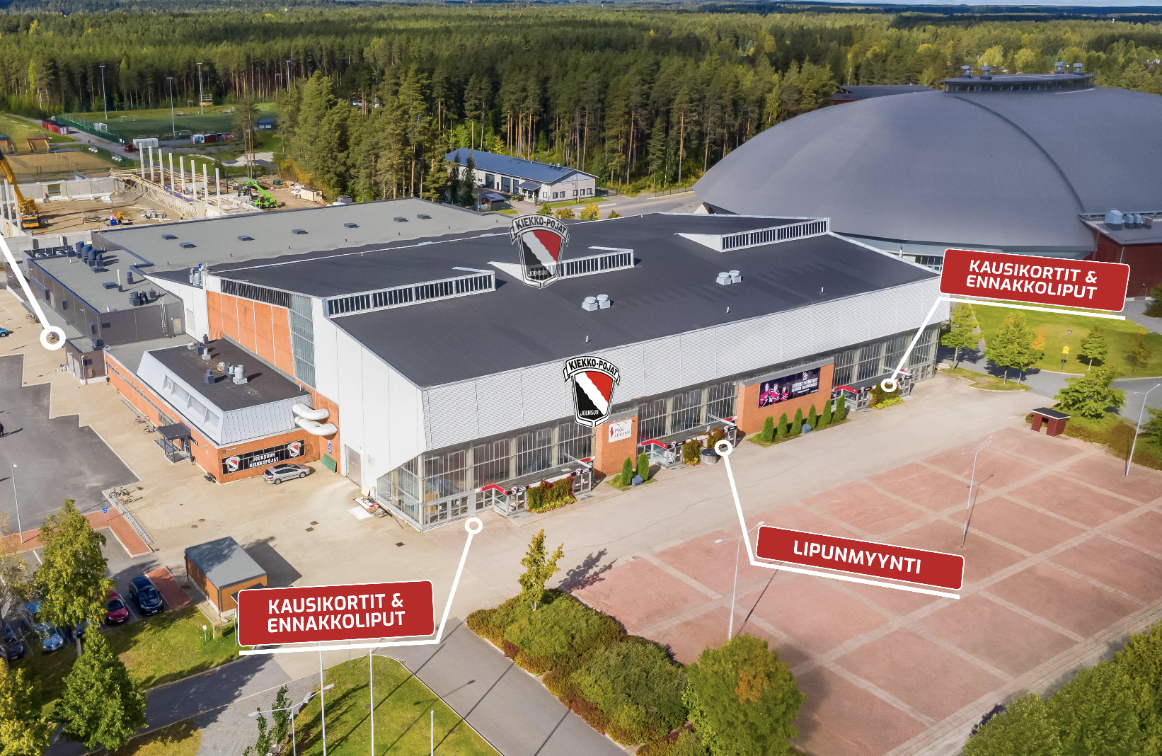 Aerial view of an indoor sports arena surrounded by trees and a parking area, with Finnish text indicating ticket sales points.