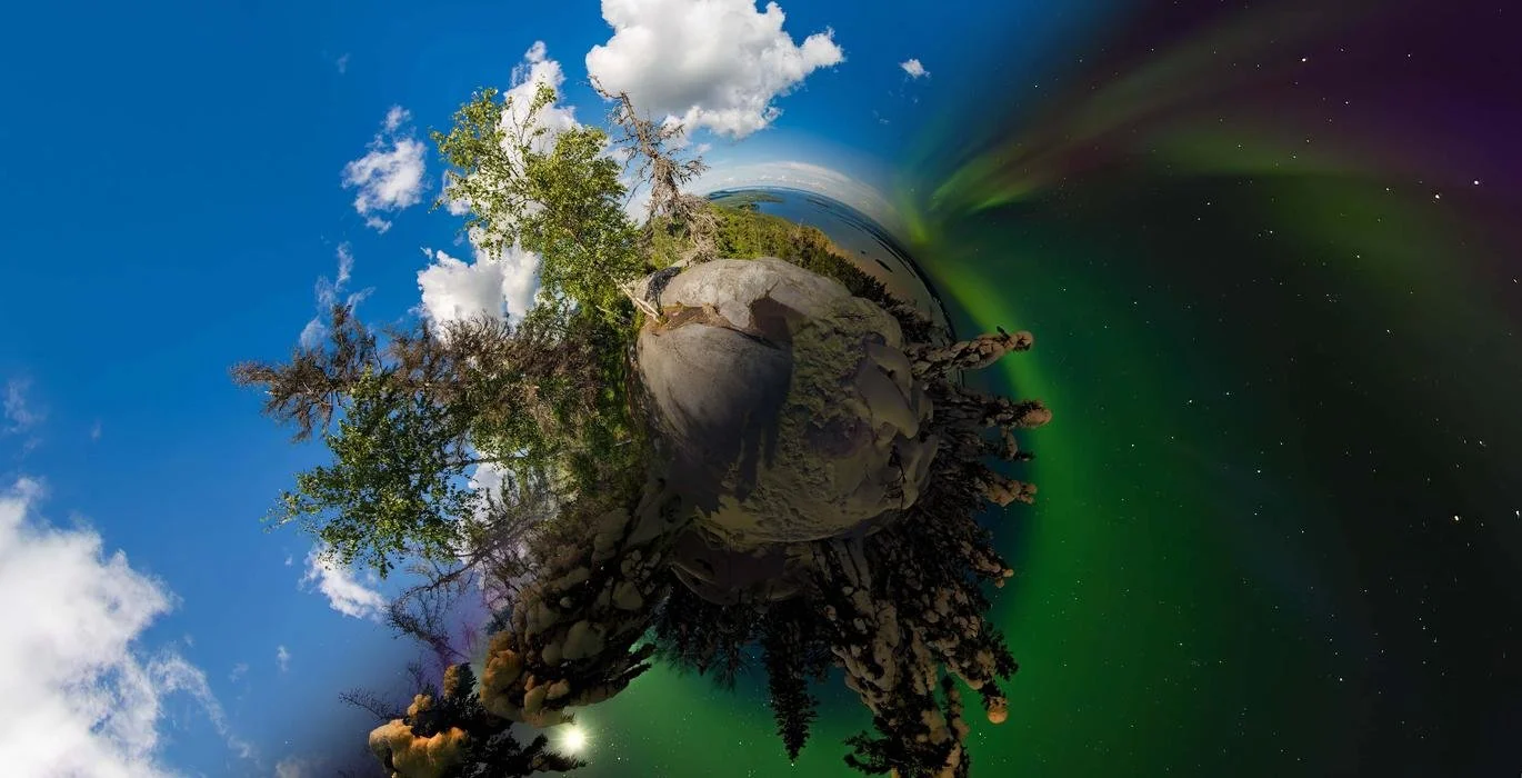 A tiny planet view of a forest landscape with green trees, rocks, and a bright blue sky with clouds on one side and the northern lights in the night sky on the other side.