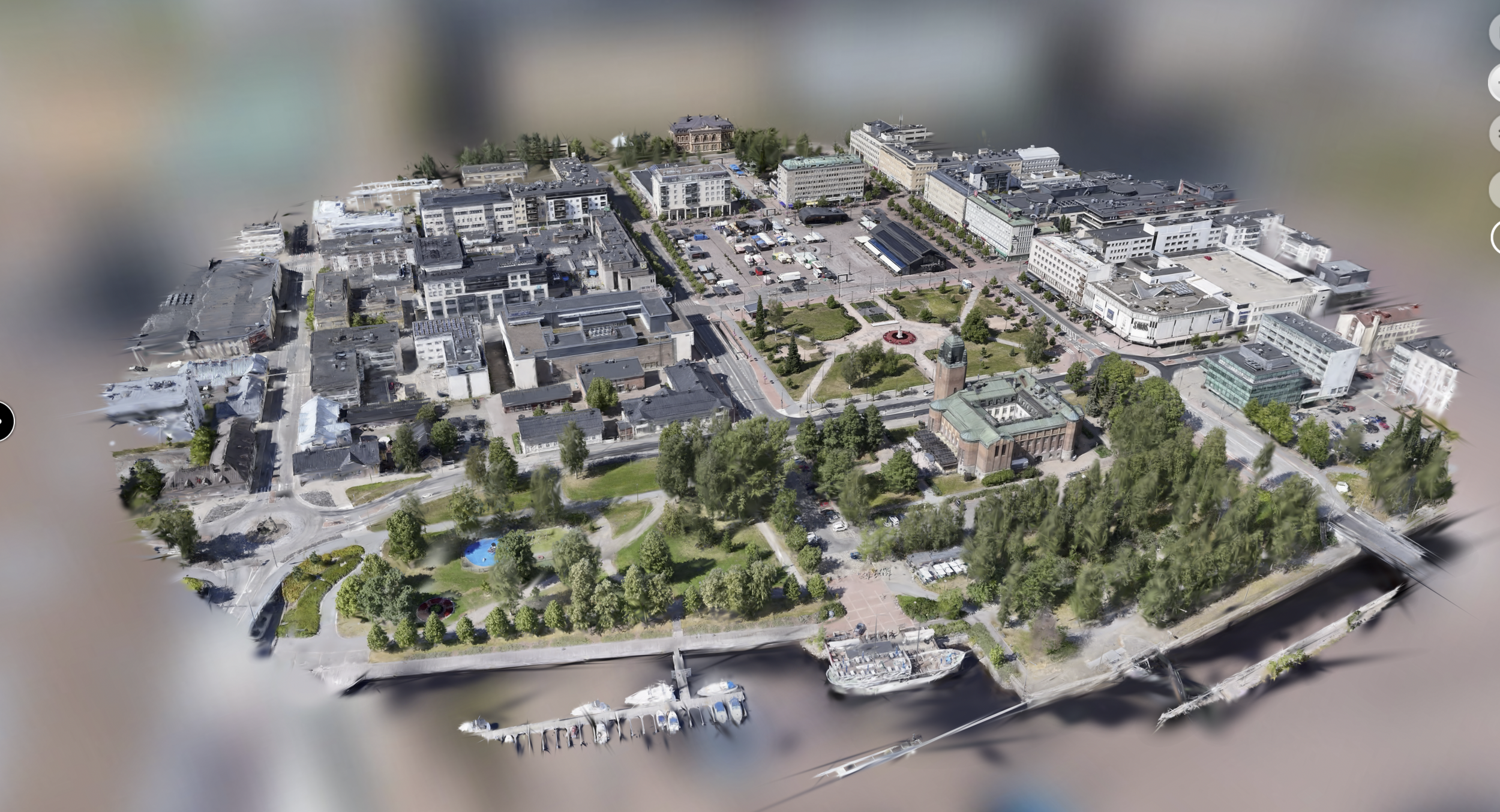 Aerial view of a town with a central park, historic buildings, modern buildings, a marina with boats, and surrounding waterways.