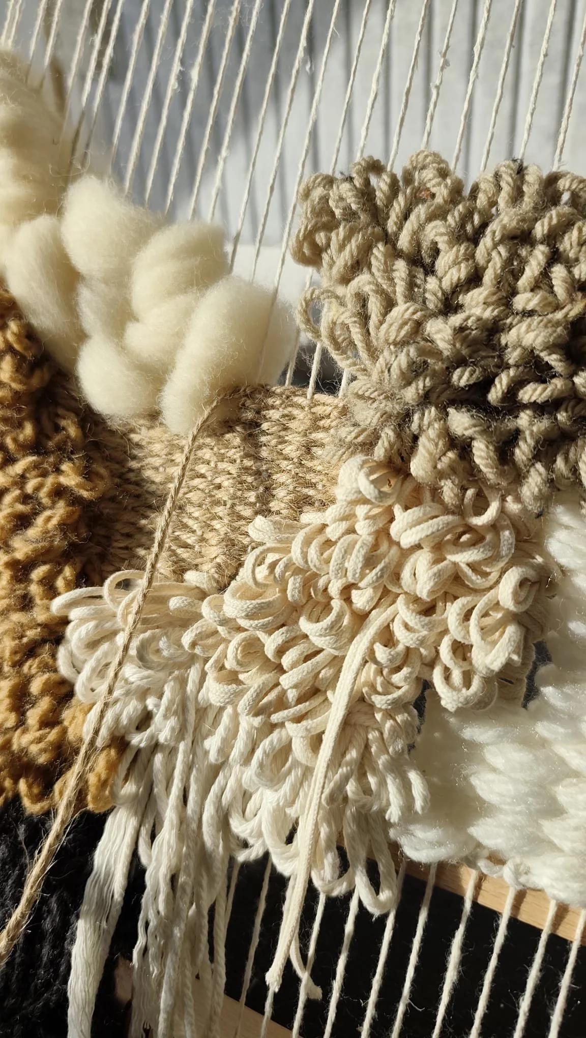 Close-up of various textured woven or knotted textile samples in beige, cream, and brown on a weaving loom.