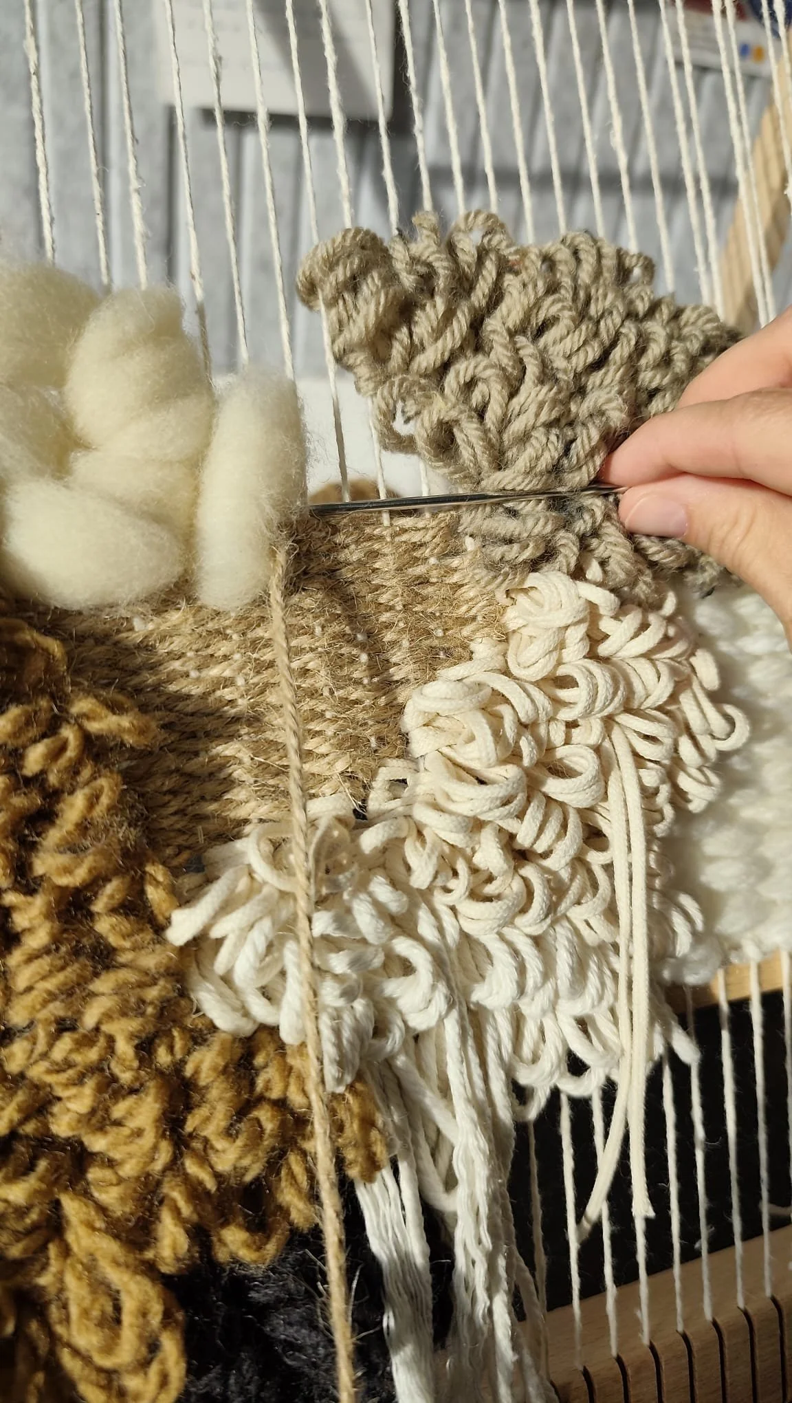Close-up of various textured yarns hanging on a weaving loom.