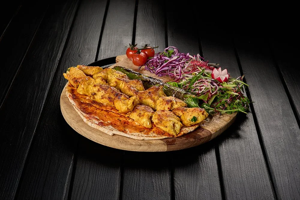 Pizza met kip, salade met rode ui, radijs, tomaten en groene chilipeper op een houten bord