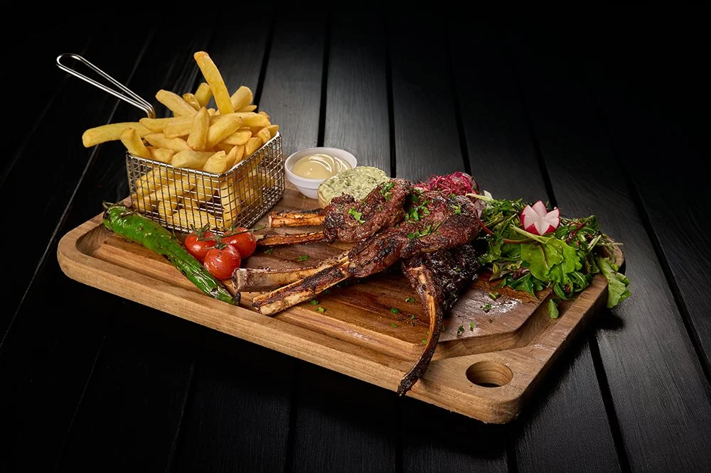 Gegrilde vleesgerechten met friet, salade, groenten en saus op houten snijplank