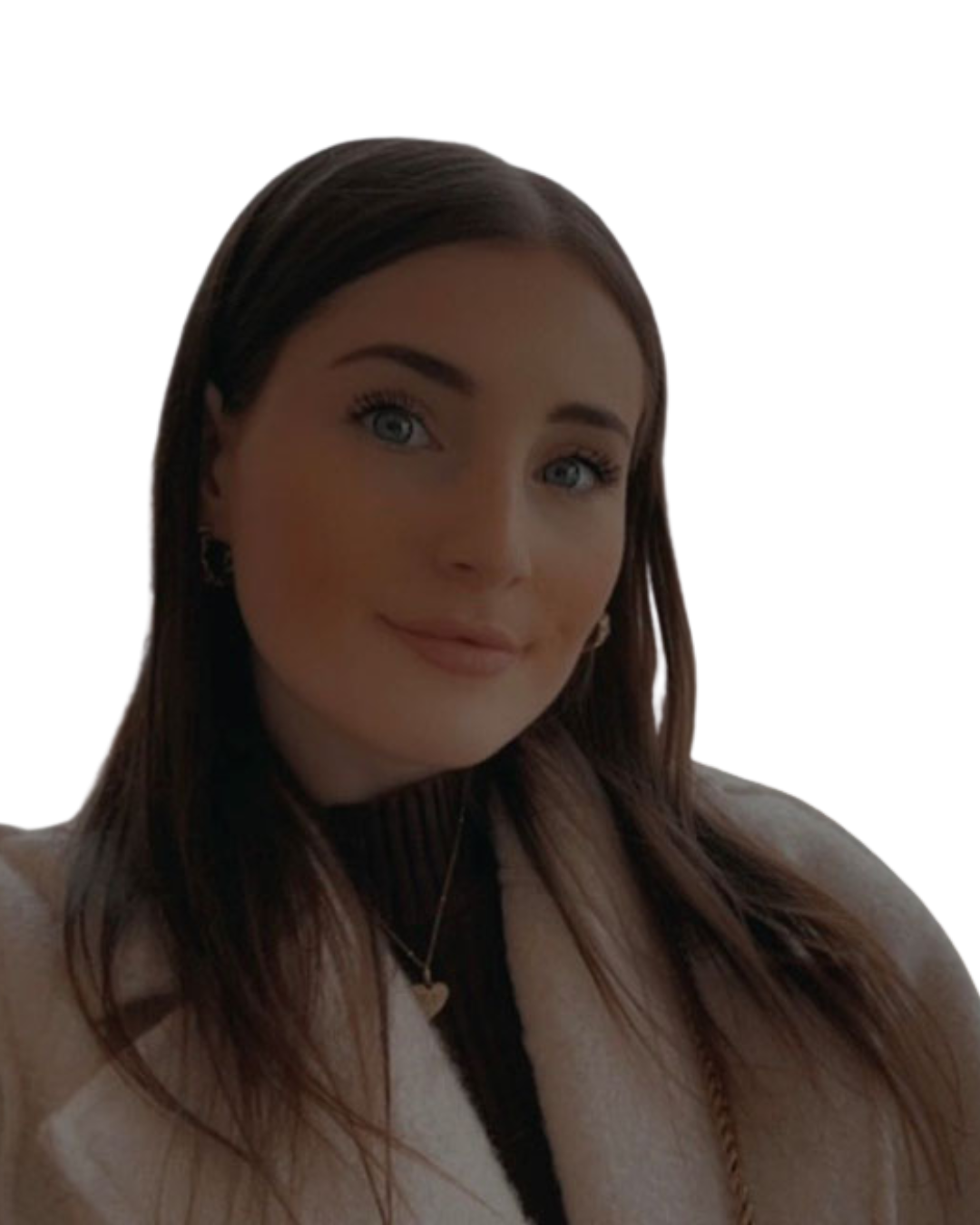 Close-up portrait of a woman with blue eyes, long brown hair, wearing a beige coat and a black top. She has a necklace with a heart-shaped pendant and earrings, smiling gently.