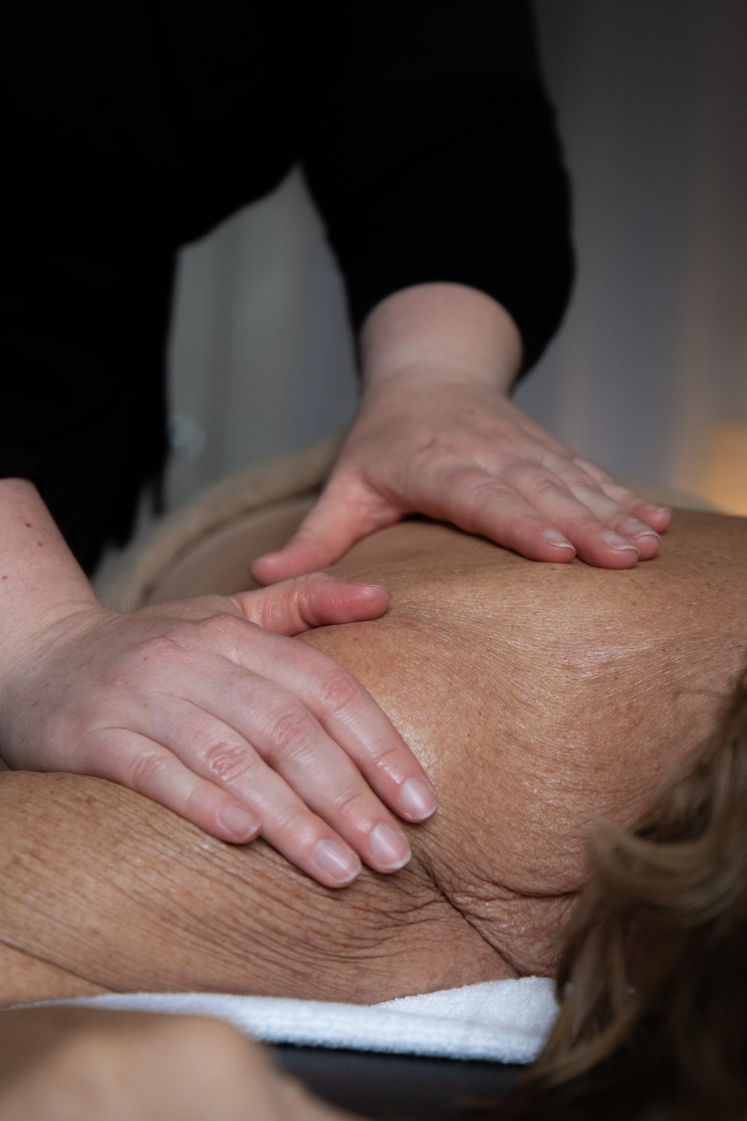 Close-up of a person receiving a back massage, with the massage therapist's hands on their back.