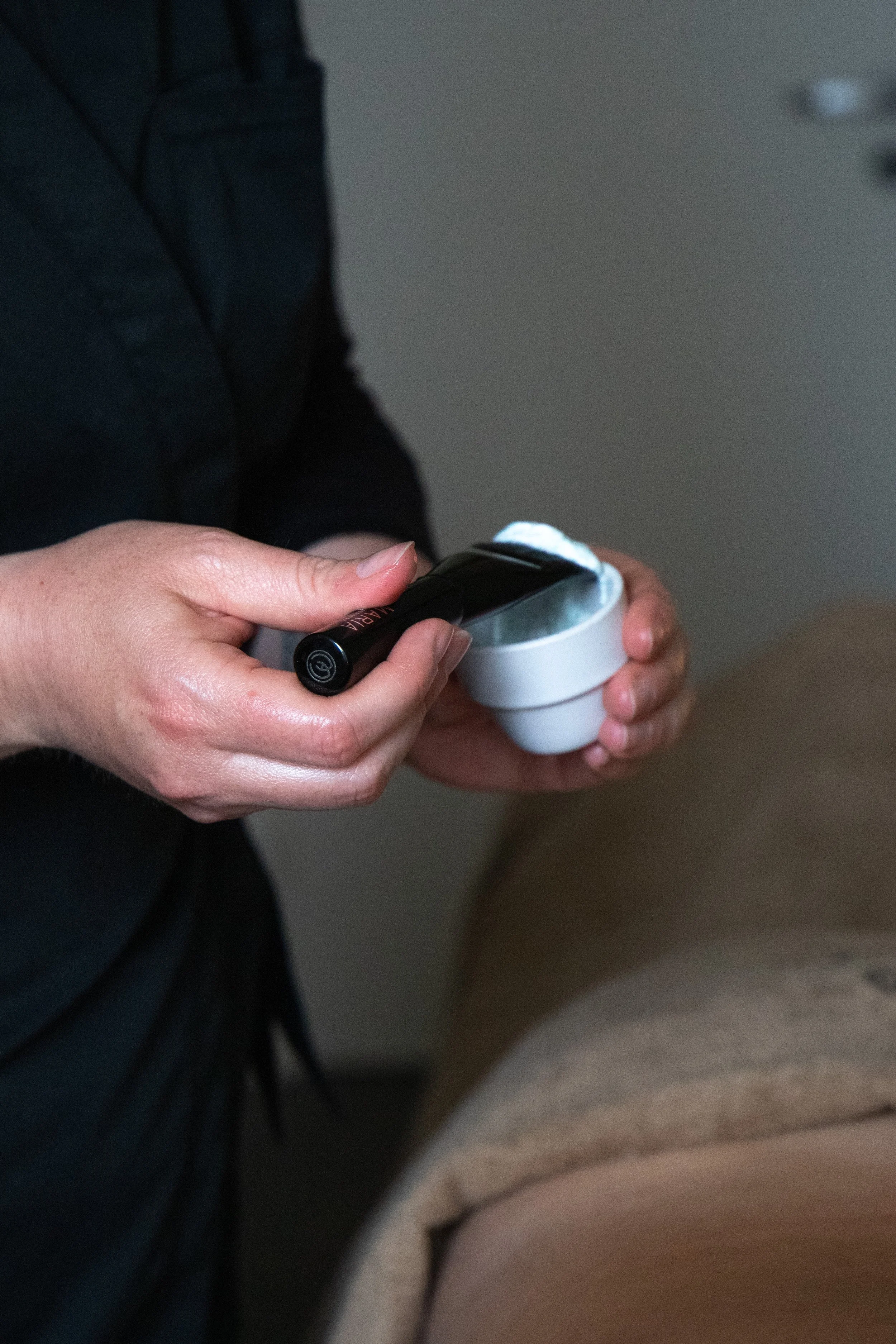 Person holding a black flashlight and a white container.