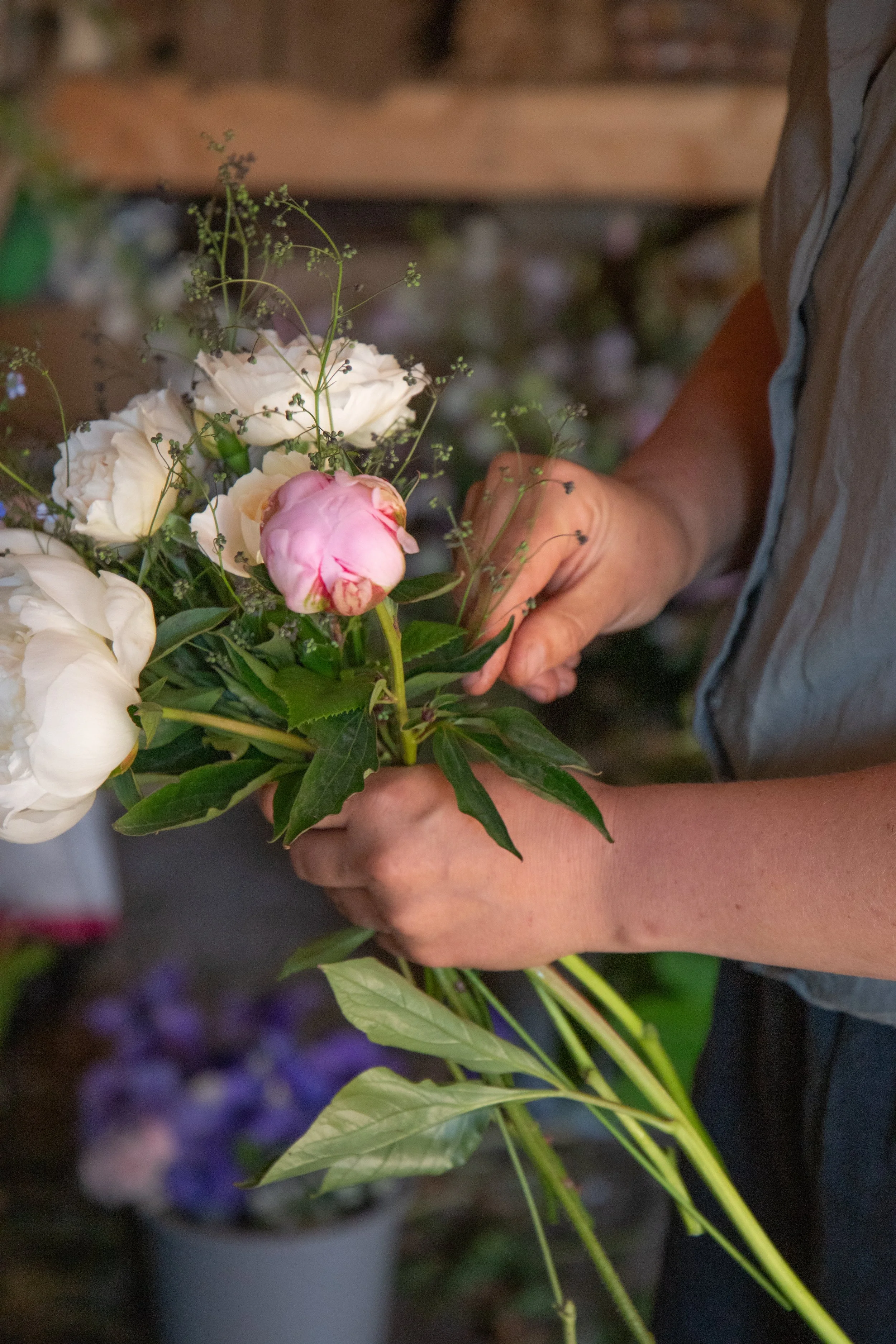 Person arranging a bouquet of mixed white and pink flowers.