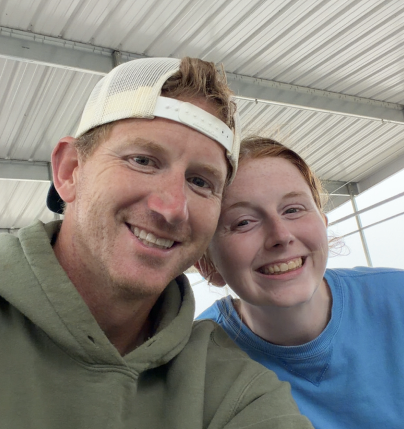 A man and woman smiling for a photo under a metal roof.