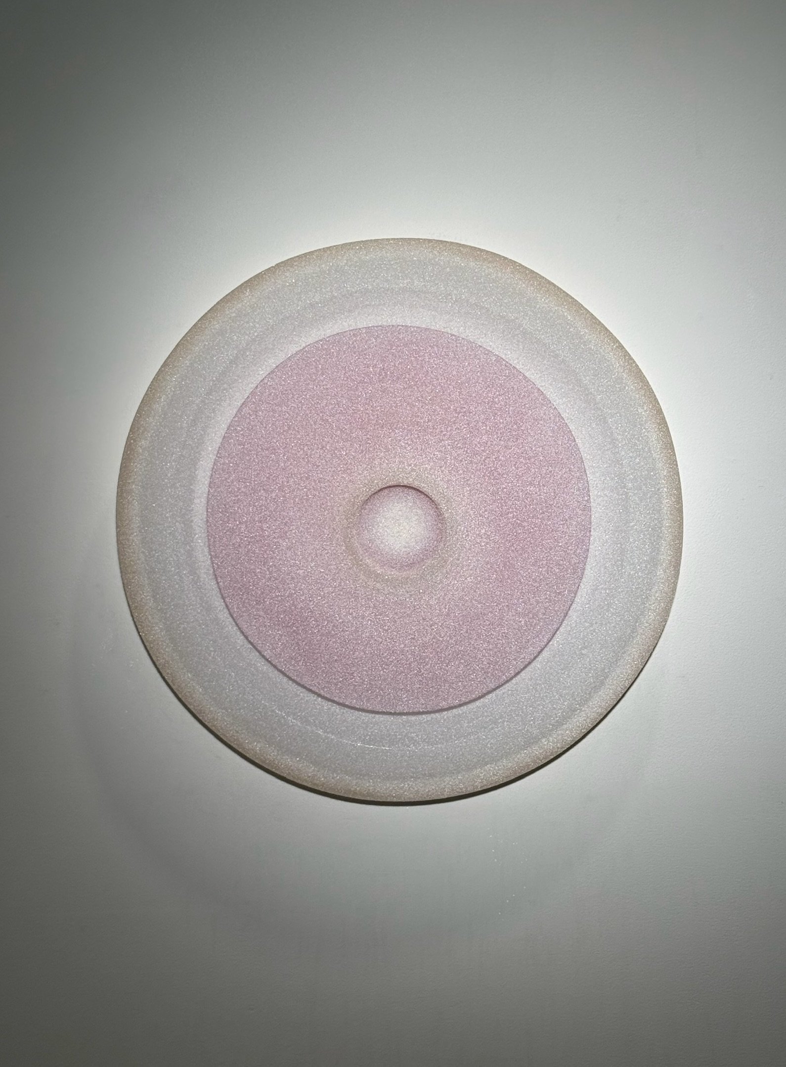 Close-up of a vinyl record with pink label, viewed from above, on a white background.