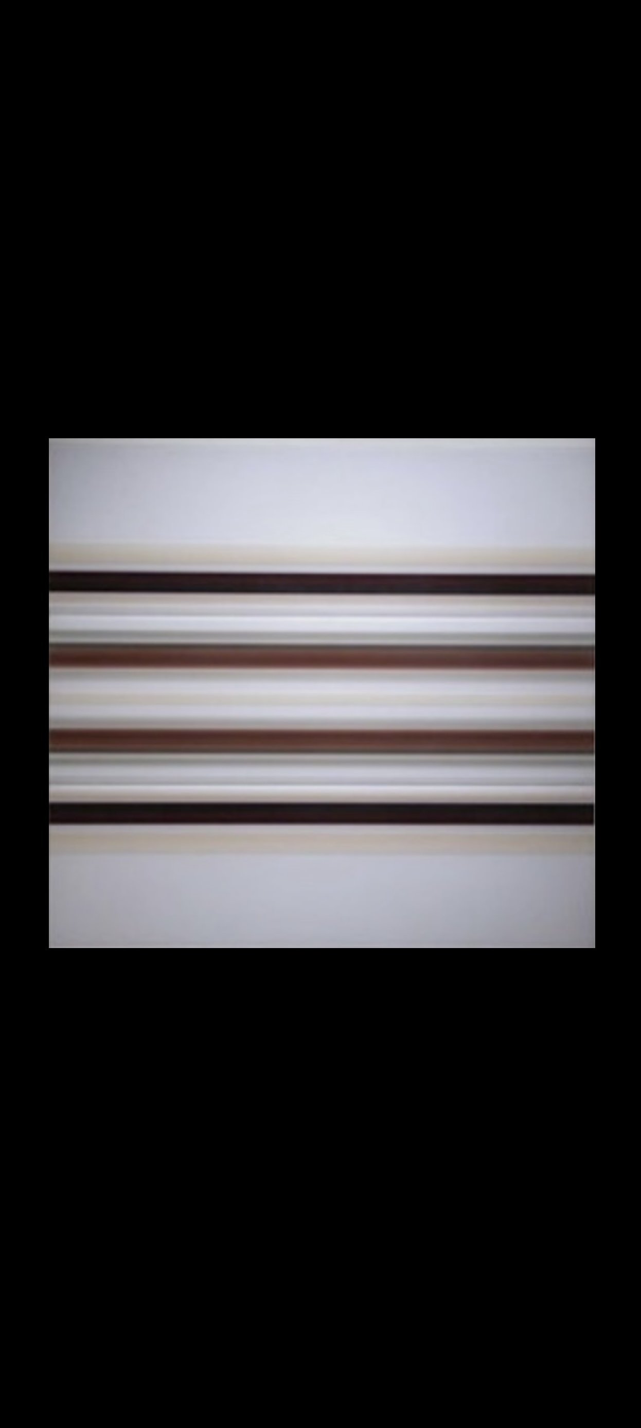 Close-up of white shelf with several horizontal rows of brown and beige railings, mounted on a white wall.