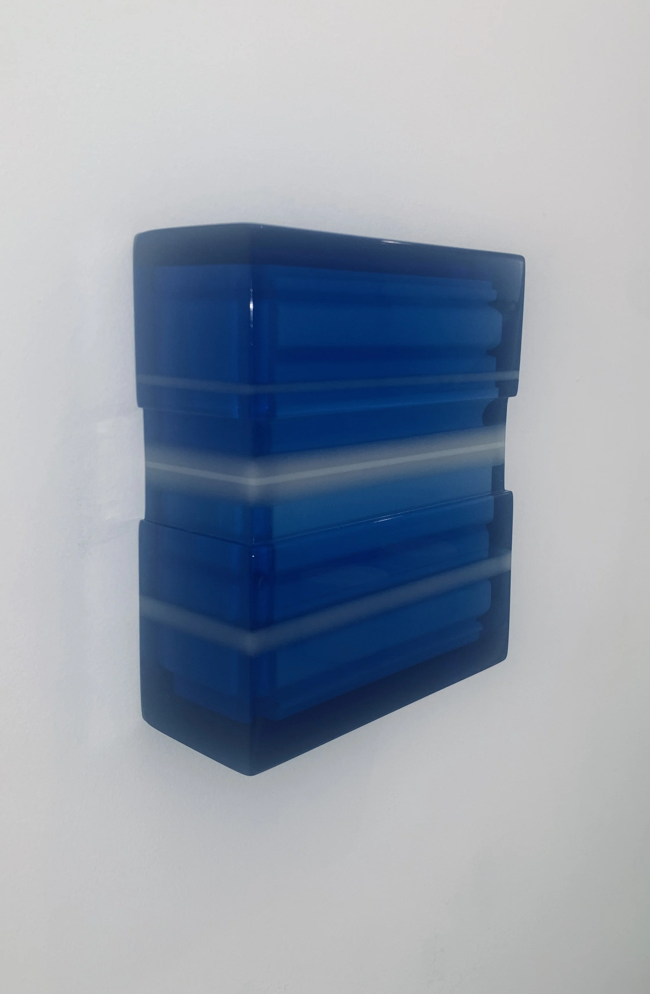 A stack of blue plastic storage containers against a plain white wall.