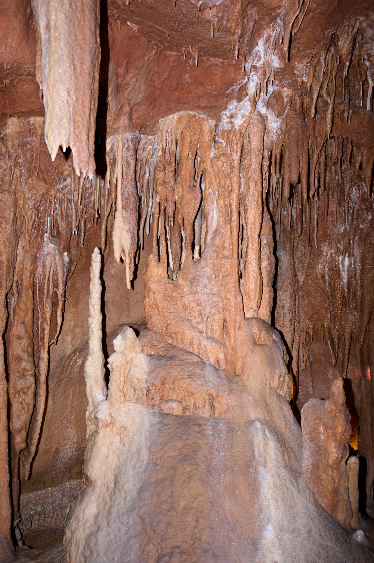 Inside a cave with orange and brown stalactites and stalagmites.