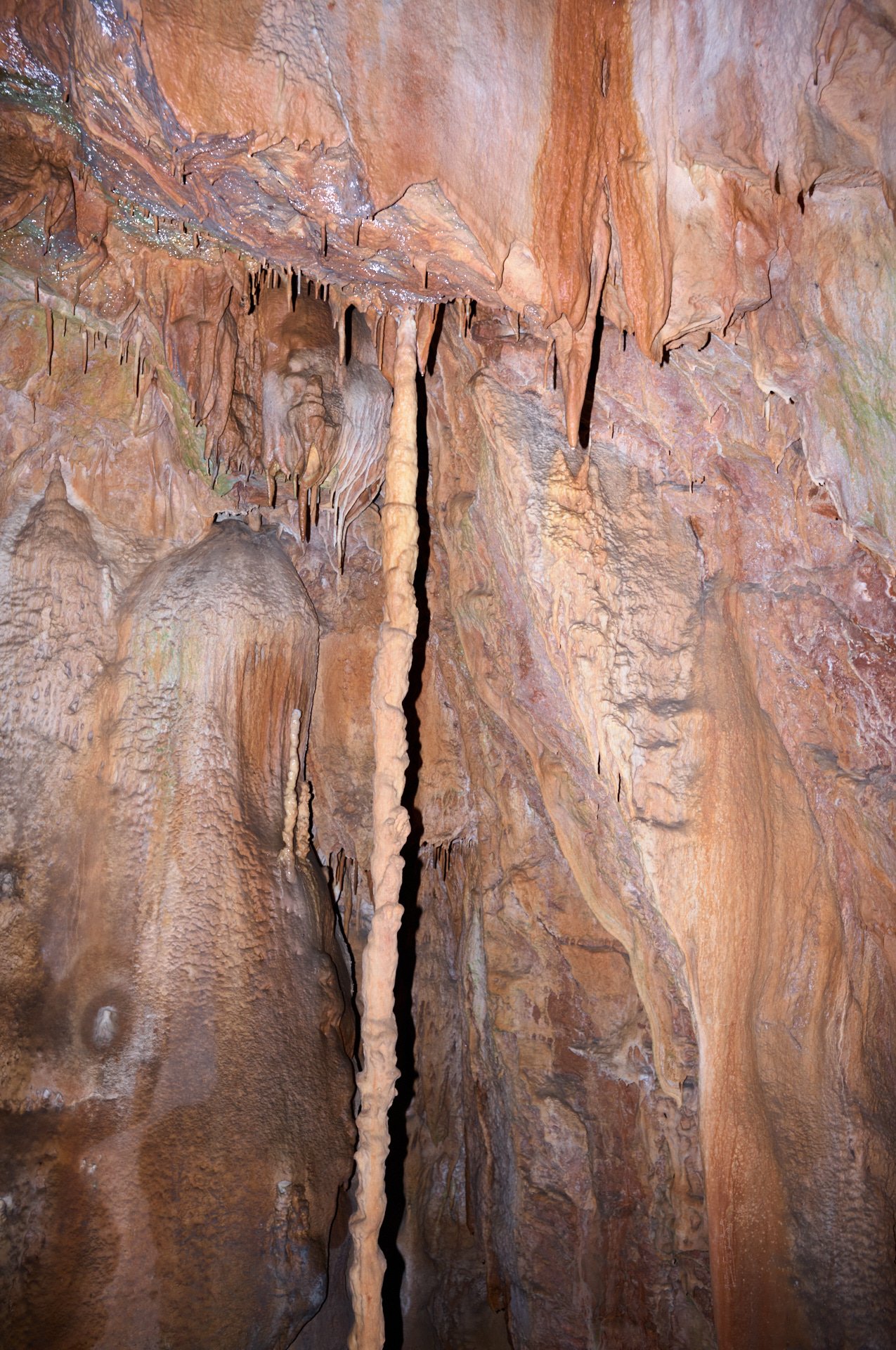 Stalactites and stalagmites inside a limestone cave with orange and brown hues.