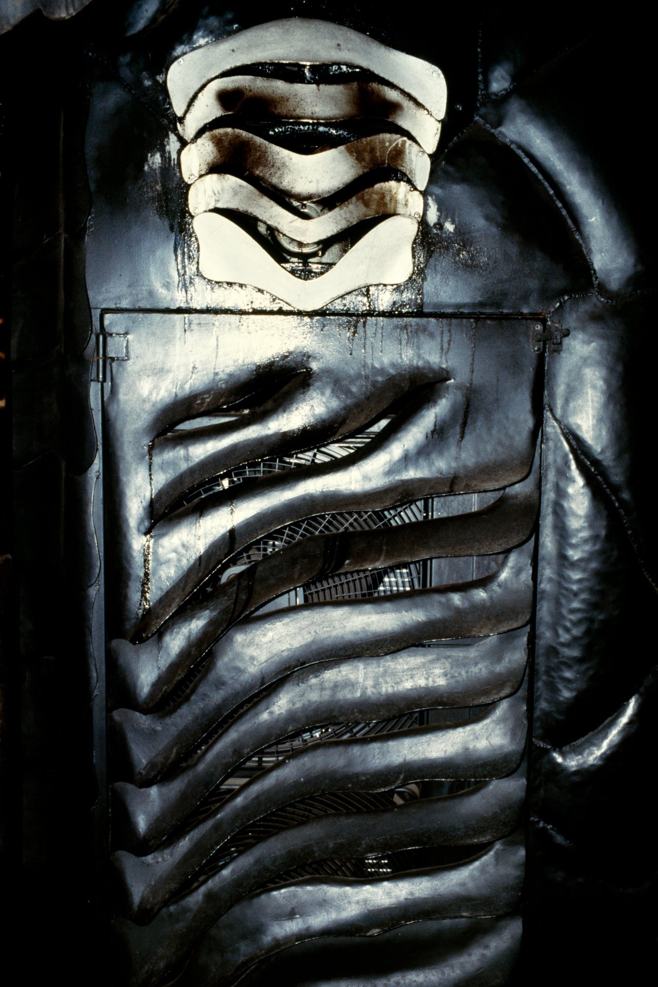Close-up of a metallic robot face with a vent-like mouth and mechanical details.